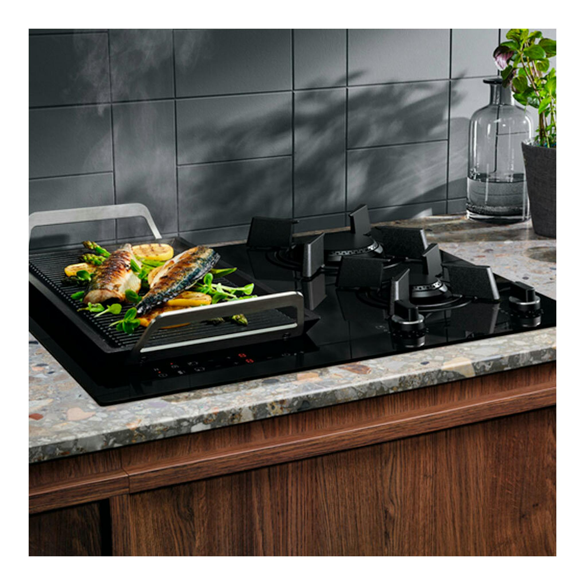 Placa de inducción Electrolux KDI641723K negra, vista en perspectiva sobre encimera, con parrilla.