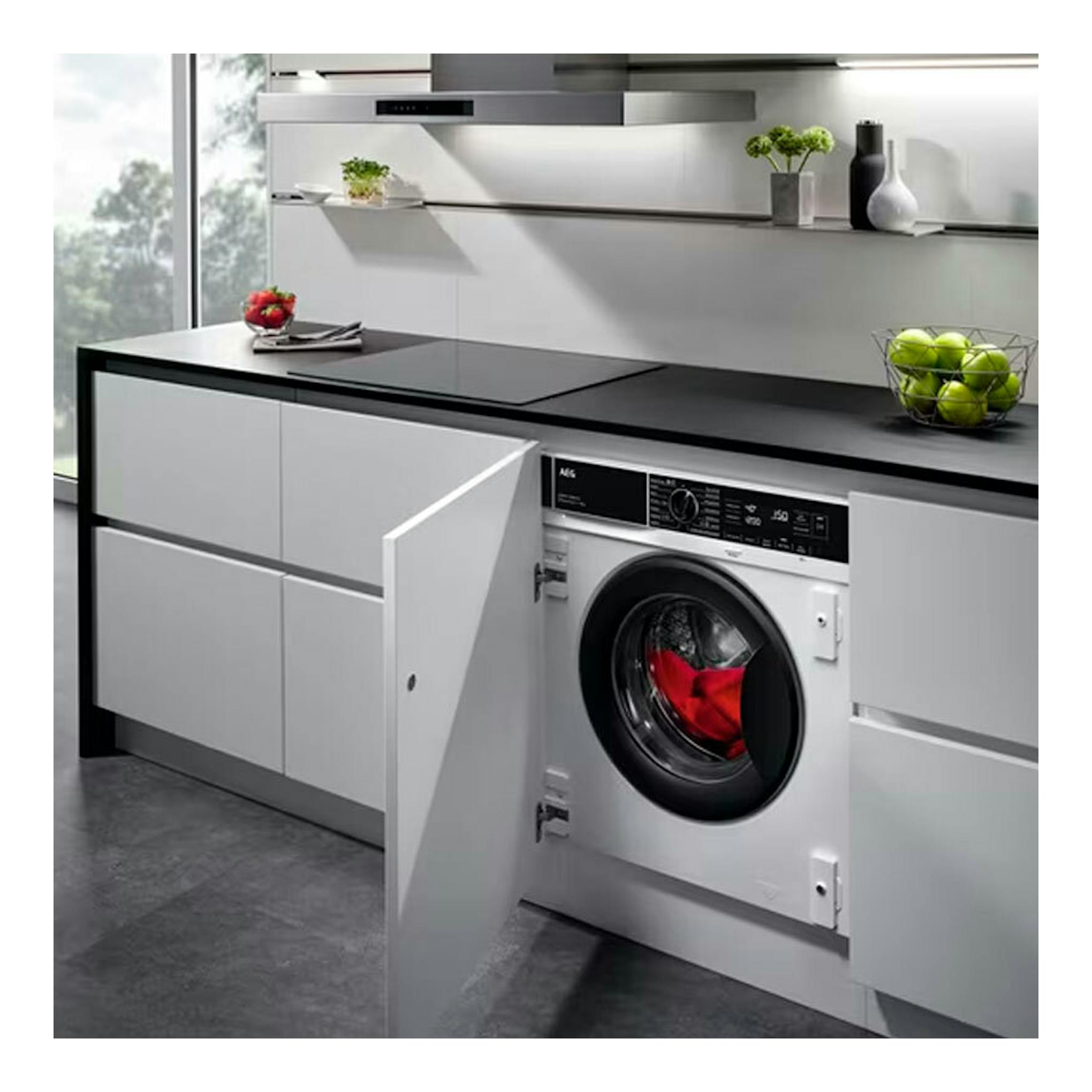 Lavadora integrada AEG LFN8E8436C blanca, vista frontal con la puerta abierta en una cocina.