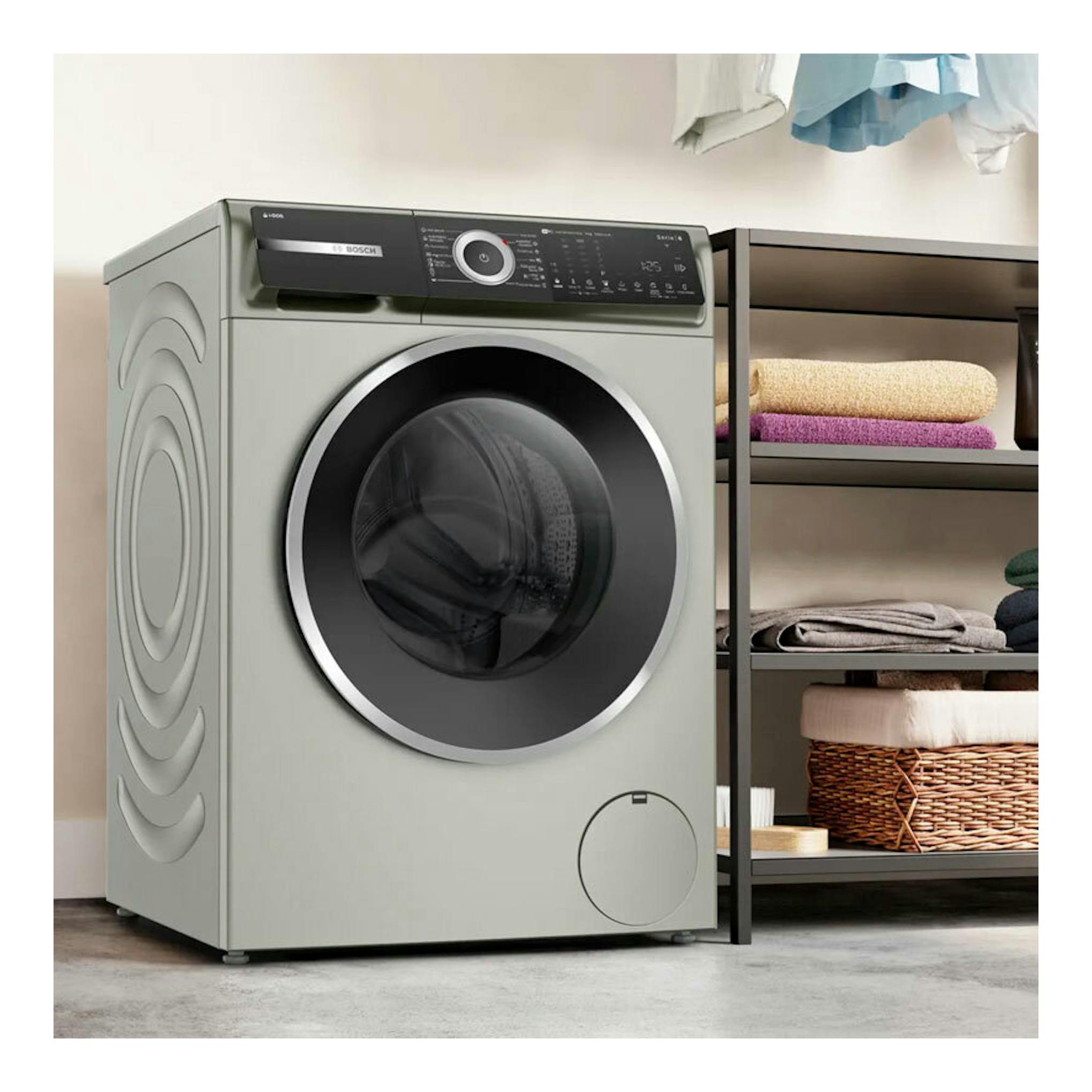 Lavadora Bosch WGH244AXES gris claro, frontal, con puerta negra de carga frontal en una lavandería.