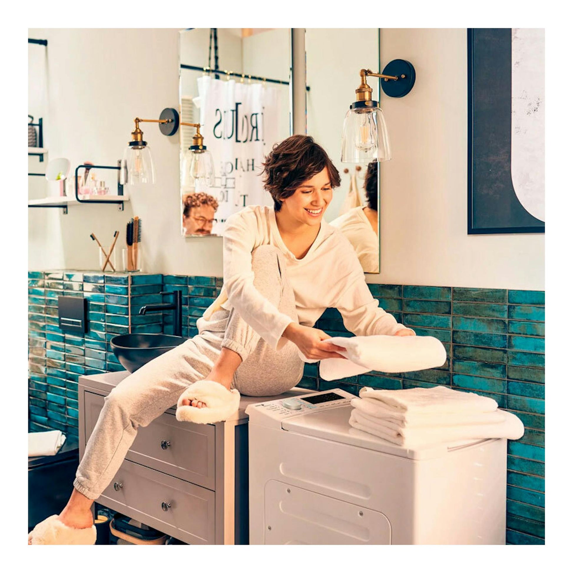 Lavadora Fagor 4FET-7112 blanca, vista frontal, con ropa doblada encima, en un baño.