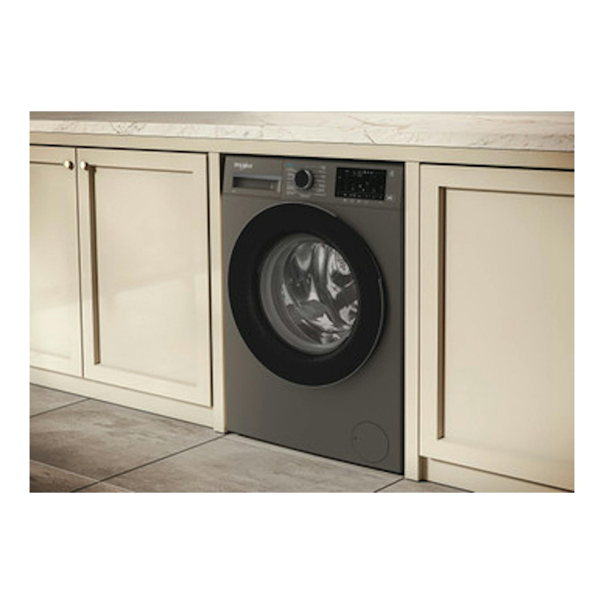 Lavadora Whirlpool WAM 07GB SPT gris, vista frontal empotrada entre muebles de cocina.
