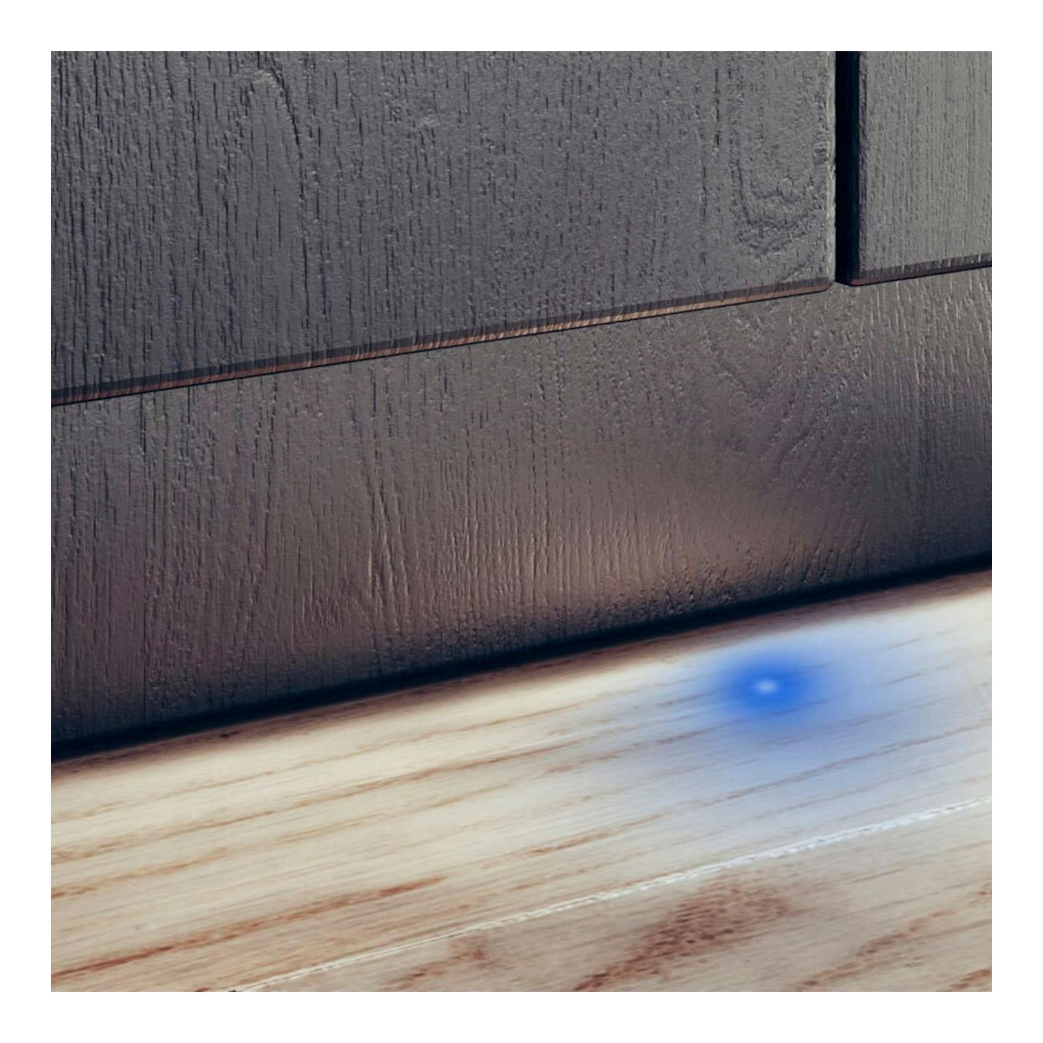 Lavavajillas integrable de frente oscuro, visto en primer plano junto al suelo de madera.
