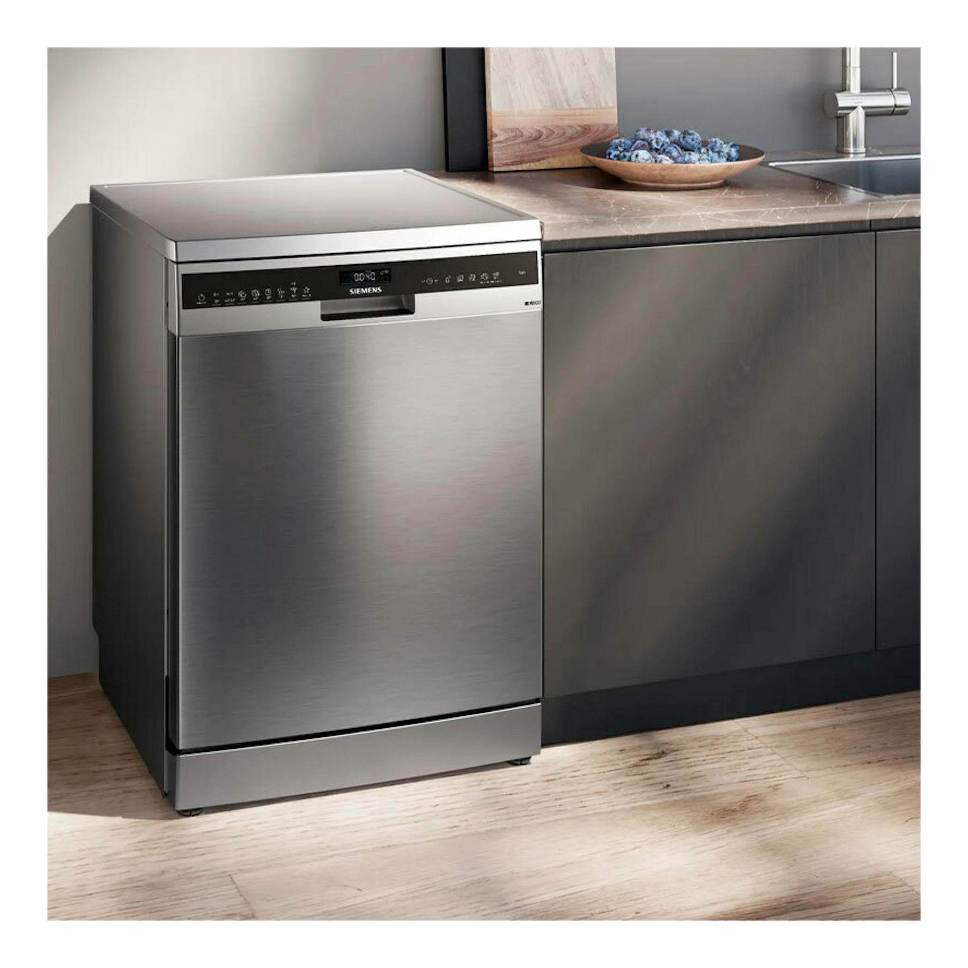 Lavavajillas Siemens SN25EI13CE inox, vista frontal en cocina moderna junto a mueble oscuro.