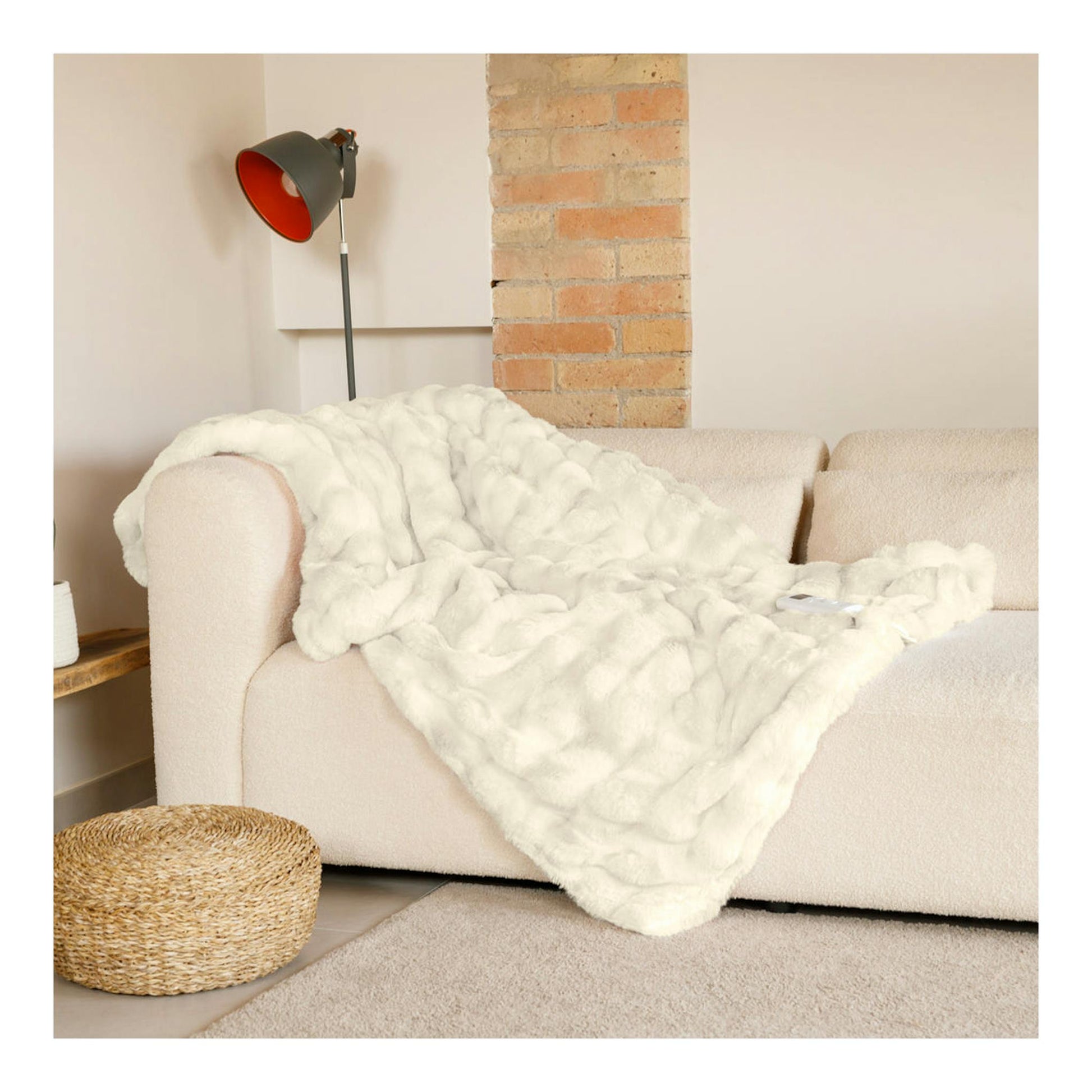 Manta eléctrica Solac Krakovia+ CT8709 blanca extendida sobre un sofá beige, en interior.