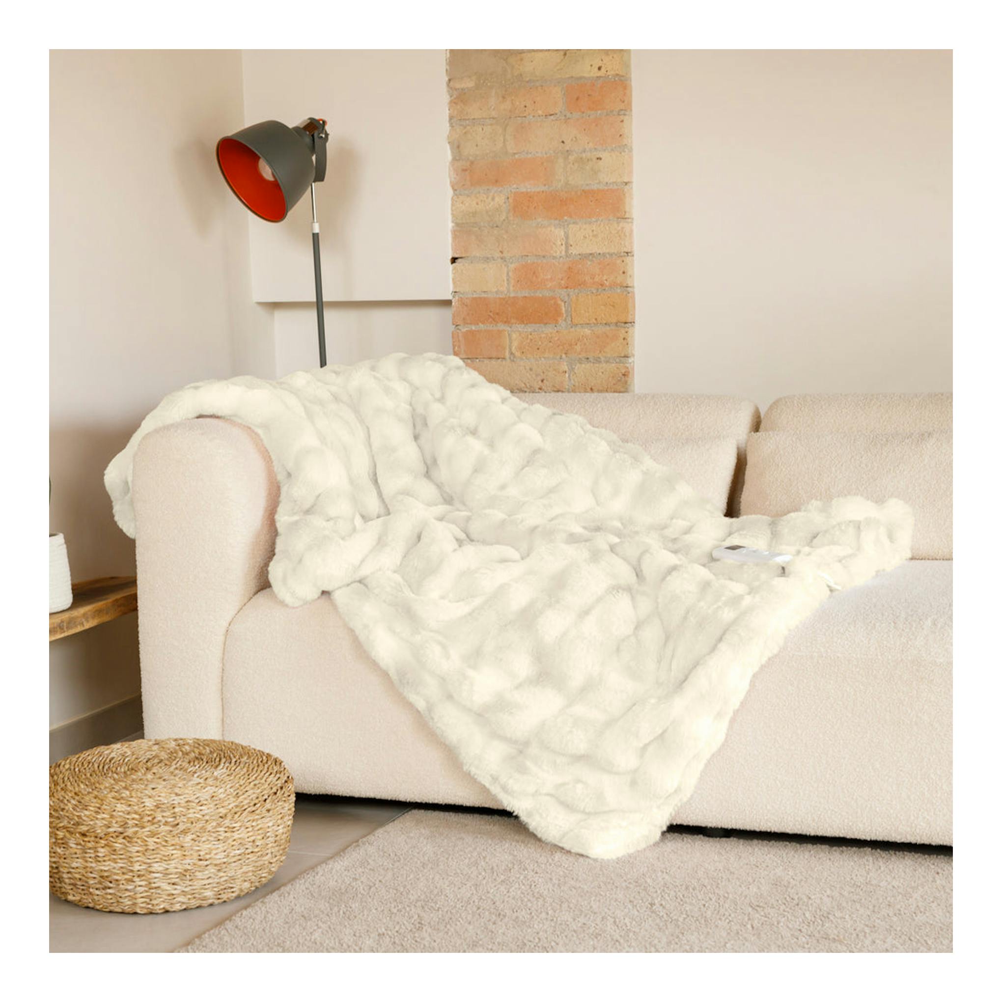 Manta eléctrica Solac Krakovia+ CT8709 blanca extendida sobre un sofá beige, en interior.