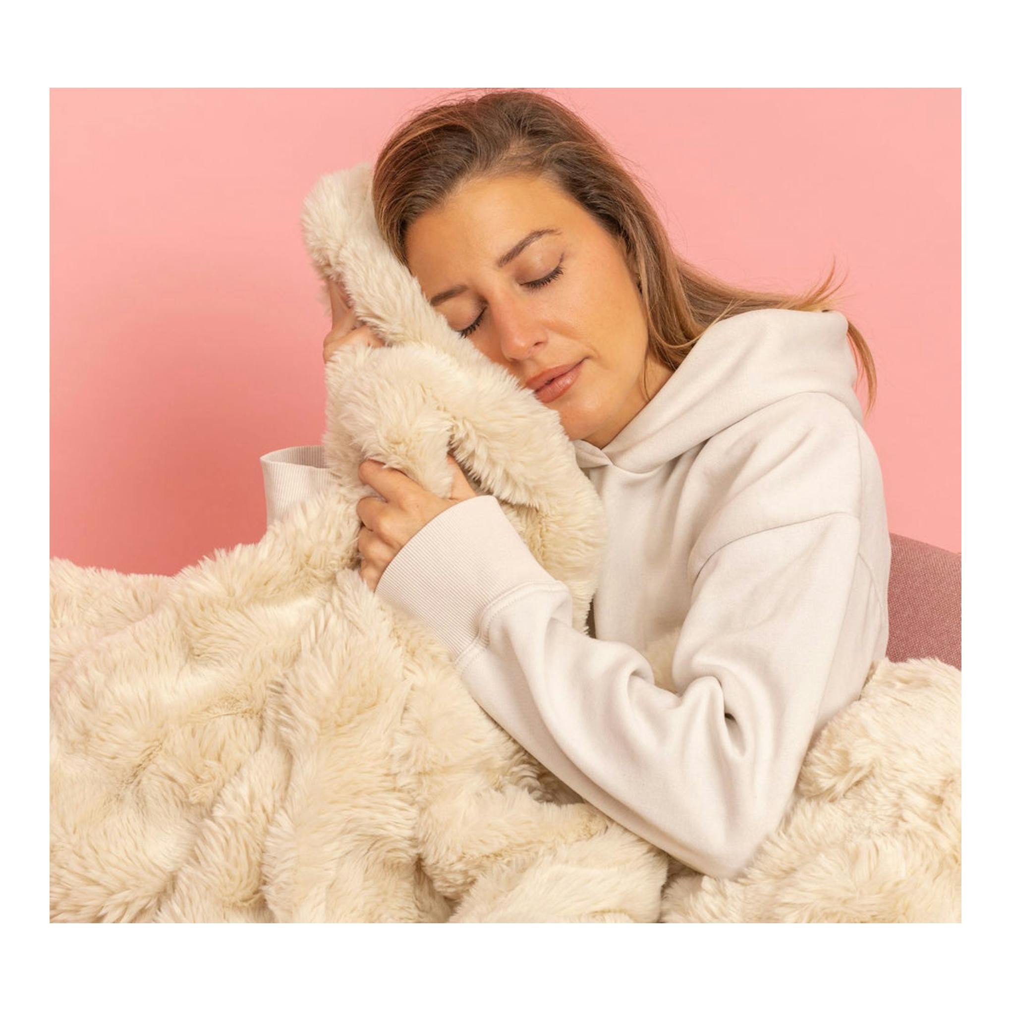 Manta eléctrica Solac Krakovia+ CT8709 beige, abrazada por una mujer con sudadera blanca.