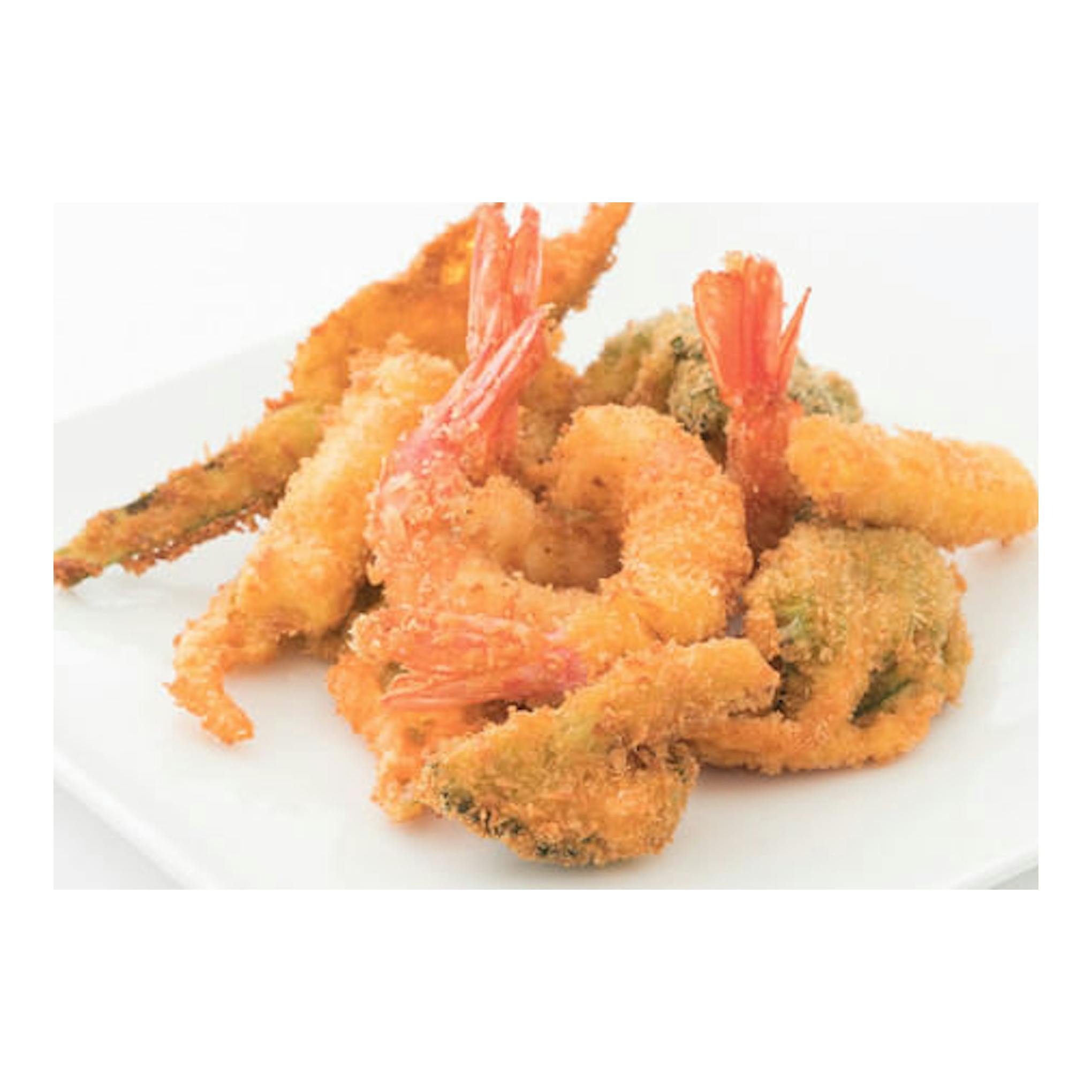 Vista en ángulo de un plato blanco con camarones empanizados fritos sobre fondo blanco.