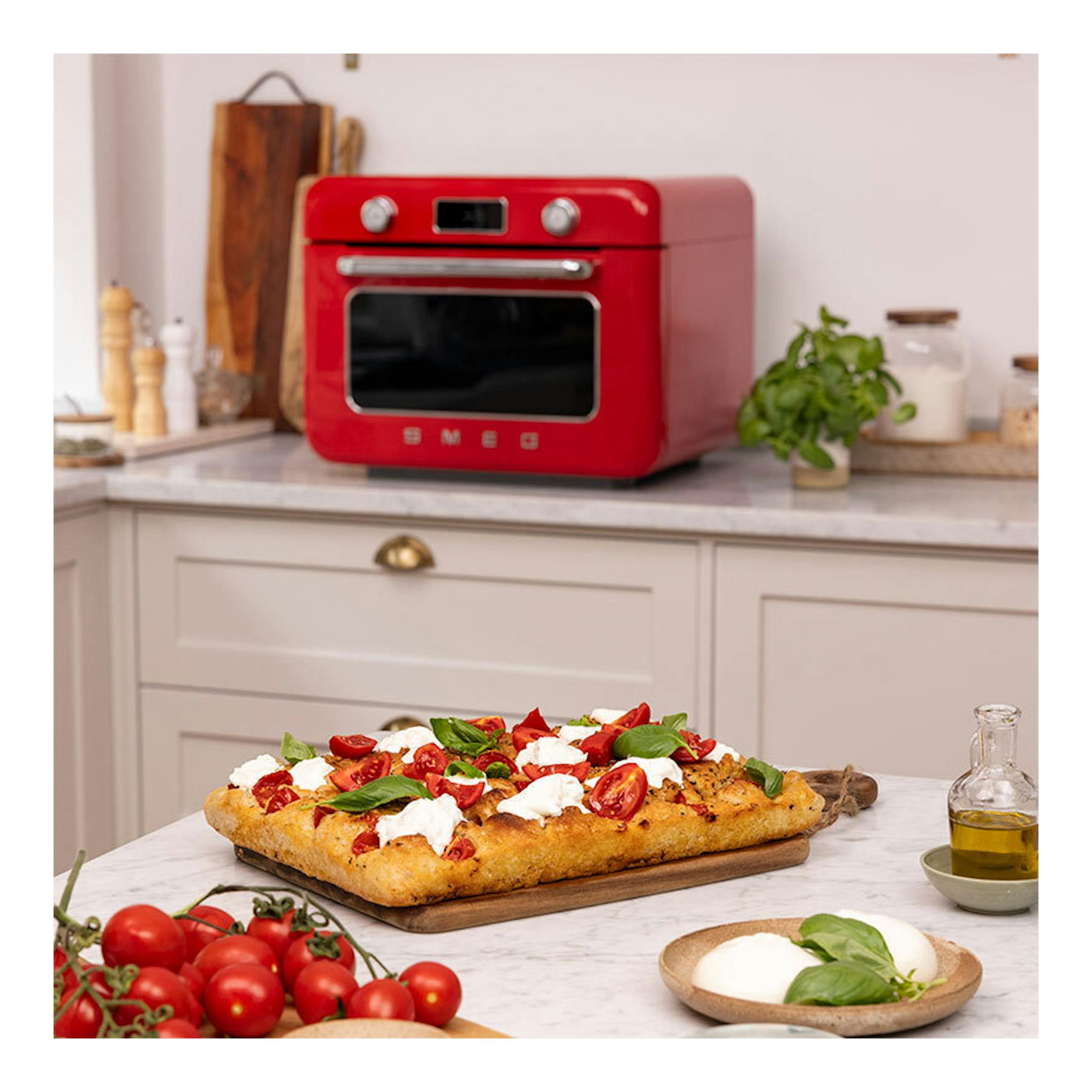 Minihorno Smeg COF01RDEU rojo, vista frontal sobre encimera de cocina.
