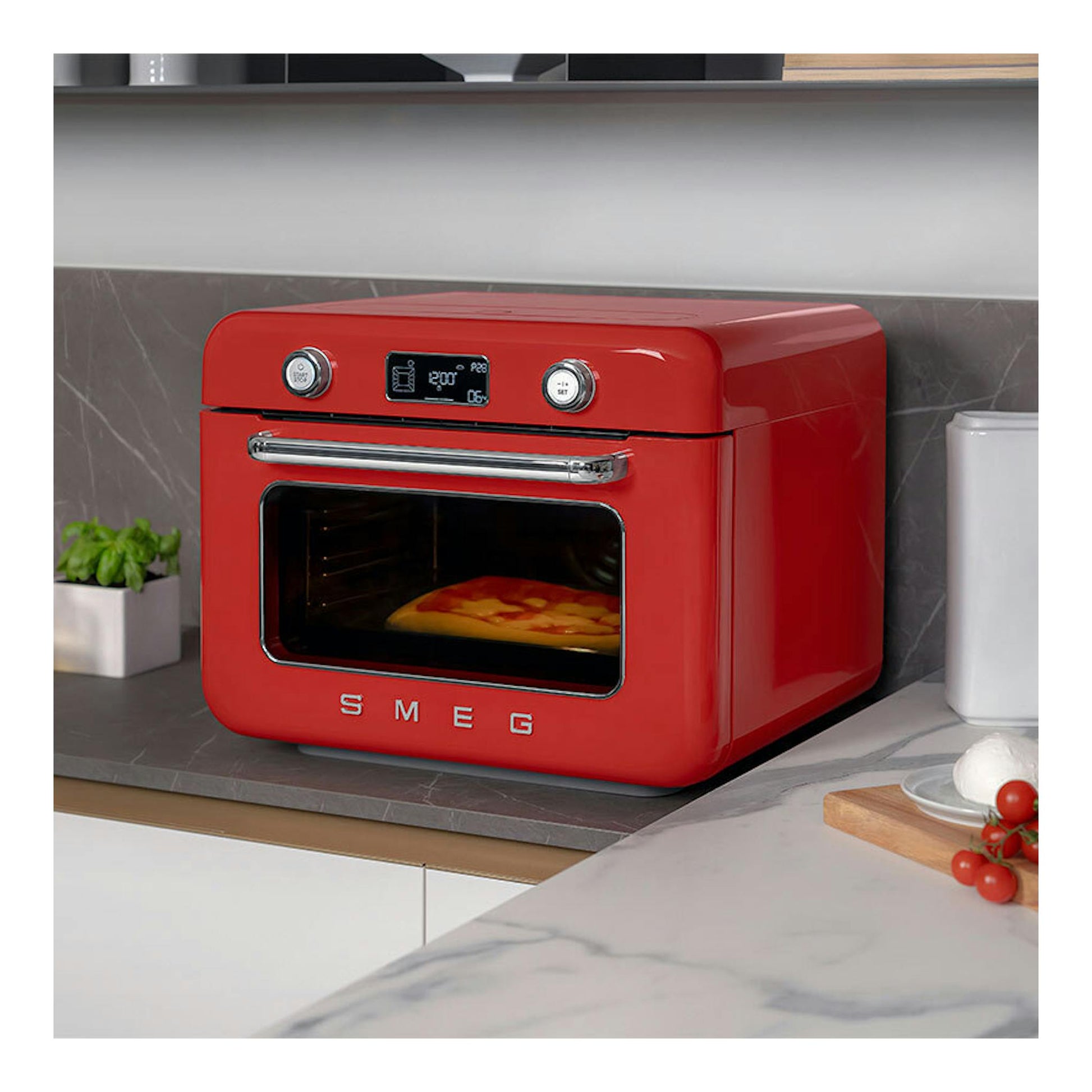 Minihorno Smeg COF01RDEU rojo, vista frontal en ángulo, sobre encimera, con pantalla digital y puerta de cristal.