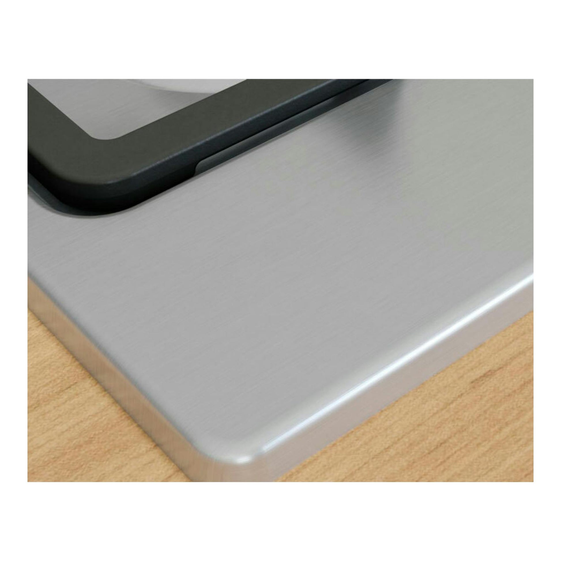 Bosch PGH6B5K90, primer plano de esquina de placa de acero inoxidable y borde negro sobre superficie de madera.
