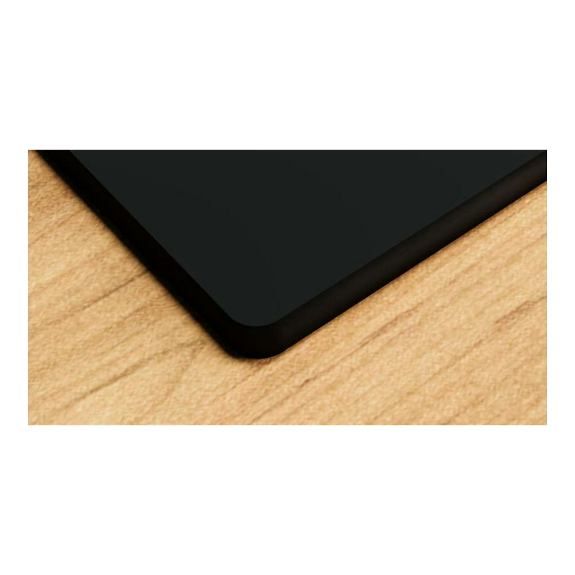 Placa de cristal Bosch PNC6B6K40 negra, vista en ángulo de la esquina sobre superficie de madera.