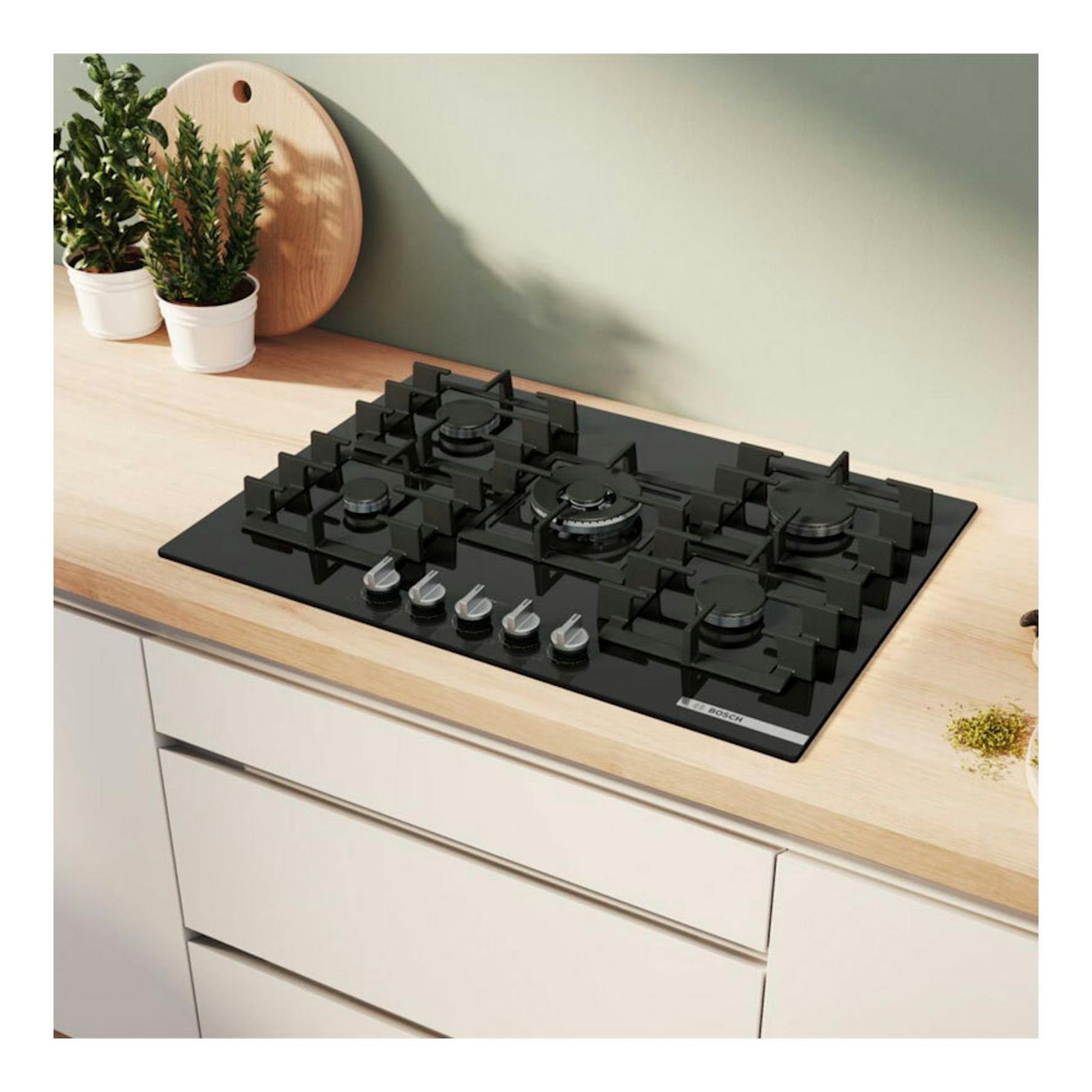 Placa de gas Bosch PPQ7A6I40 negra, vista cenital inclinada, con 5 quemadores sobre encimera de madera.