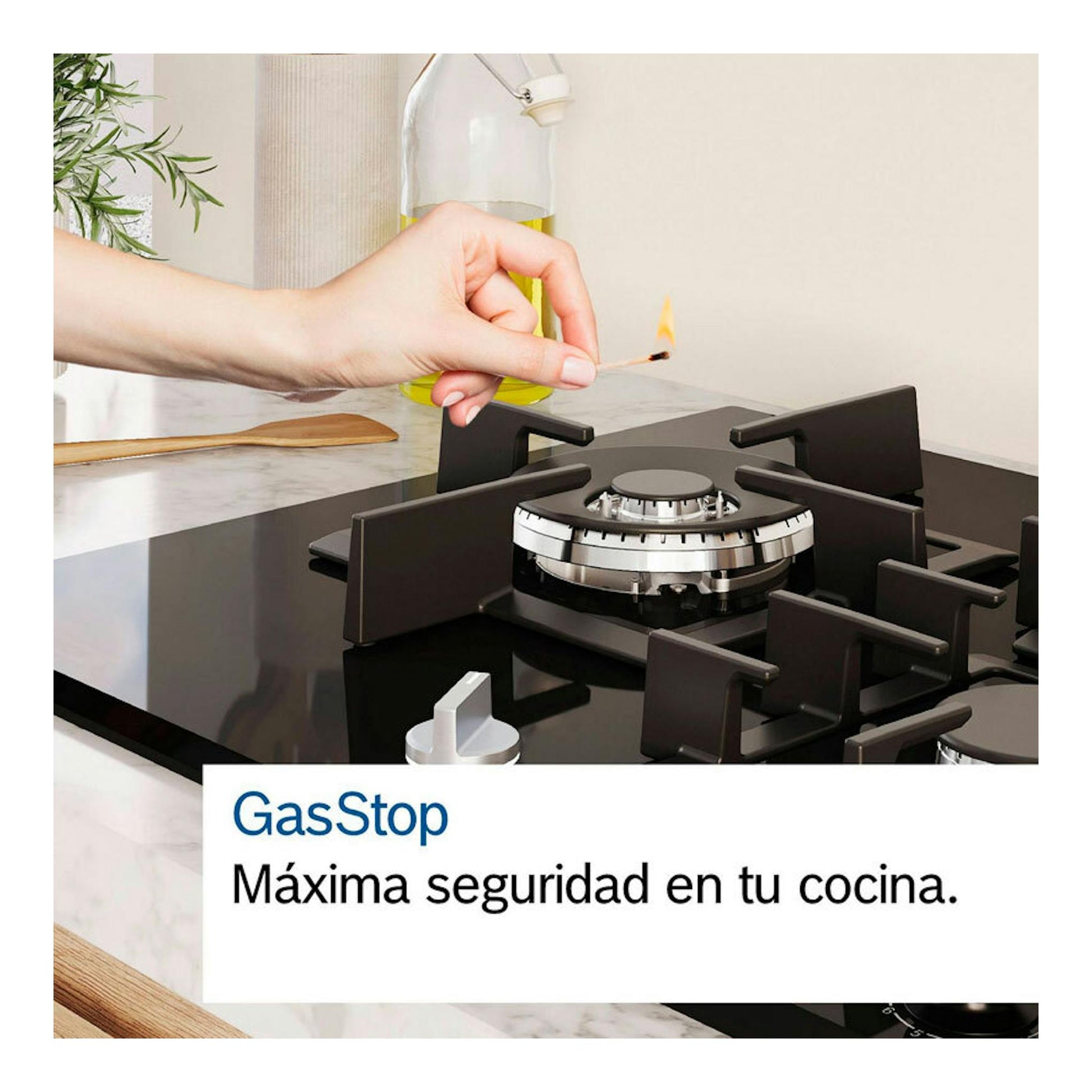 Placa de gas Bosch PRS9A6H40 negra de cristal, con un quemador encendido y una mano acercando una cerilla.