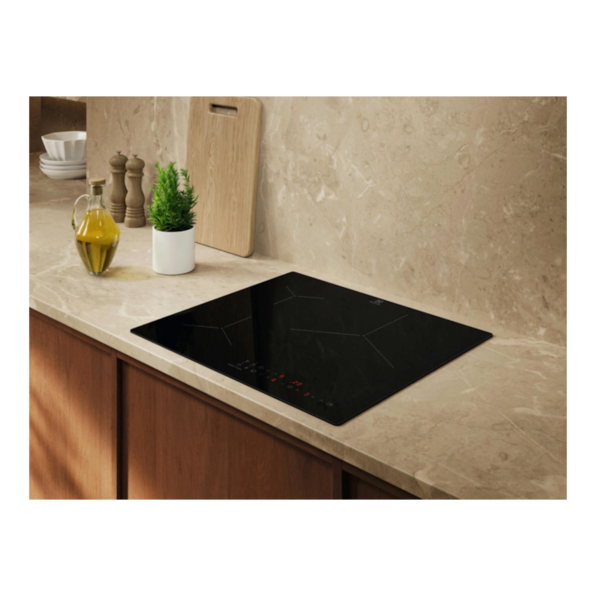 Placa de inducción Electrolux EIT61336CB negra, vista en ángulo, integrada en encimera beige.