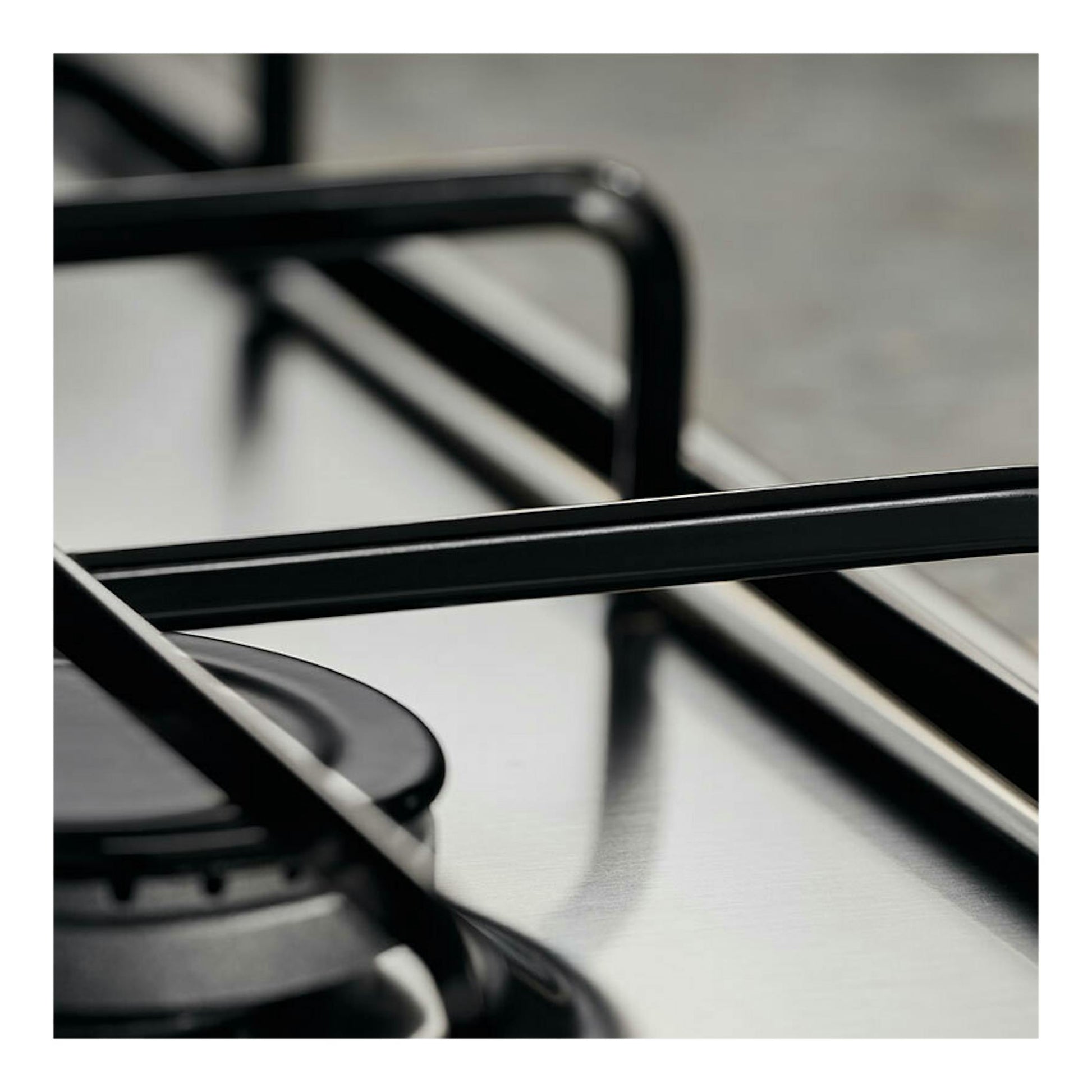 Placa de gas Electrolux KGS6404SX, vista en primer plano, con parrillas negras sobre superficie de acero inoxidable.