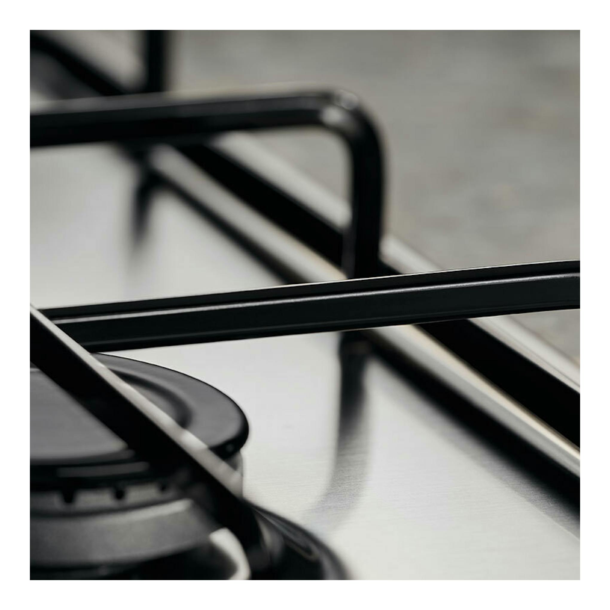 Placa de gas Electrolux KGS6404SX, vista en primer plano, con parrillas negras sobre superficie de acero inoxidable.