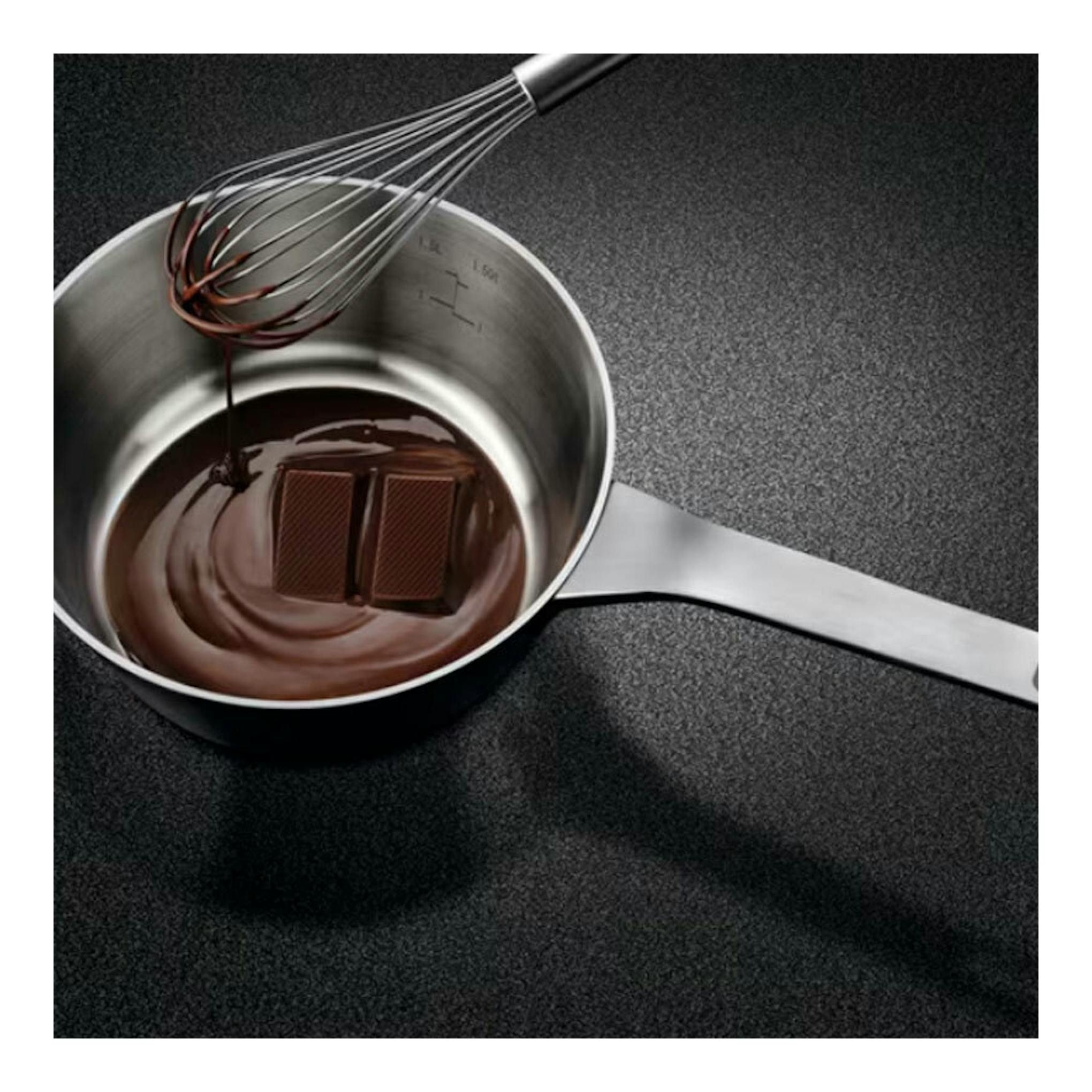 Placa de inducción AEG TI63IQ10IZ negra con cazo de chocolate y varilla de batir.