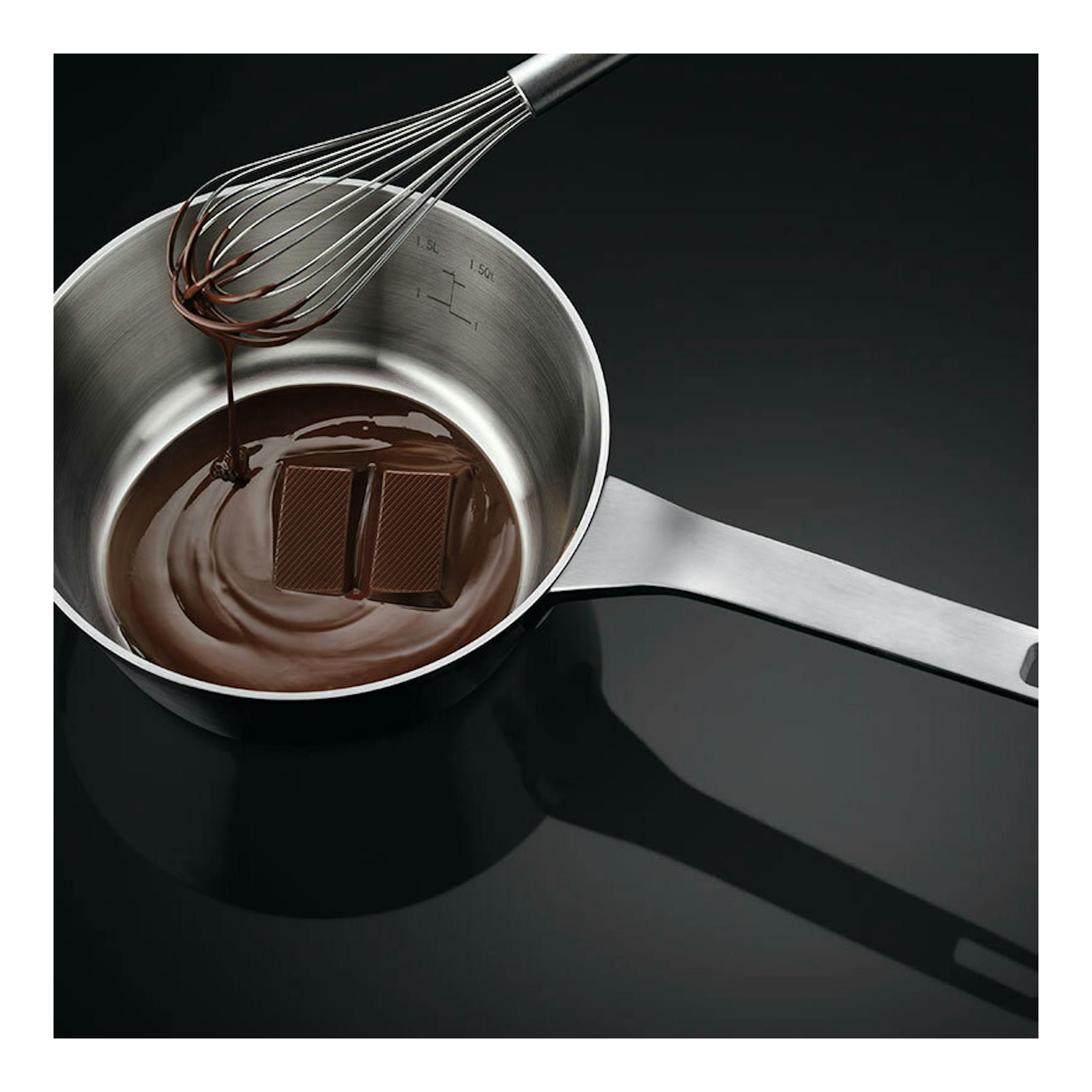 Placa de inducción AEG TN63IP0BFB negra, con cazo de acero y chocolate fundido en vista cenital.
