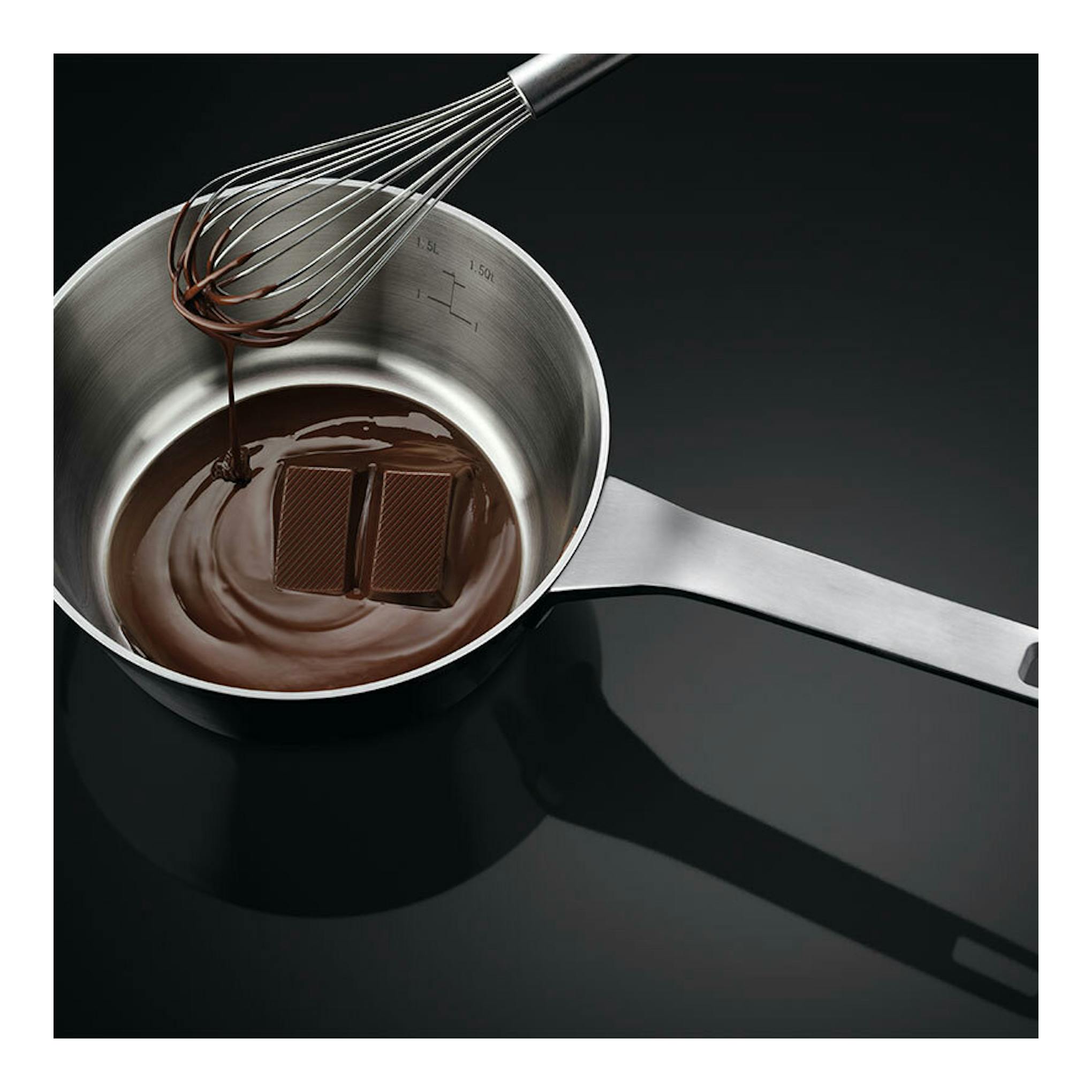 Vista superior de una placa de inducción AEG TO63IQ00FB negra, con cazo de acero, chocolate y varilla.