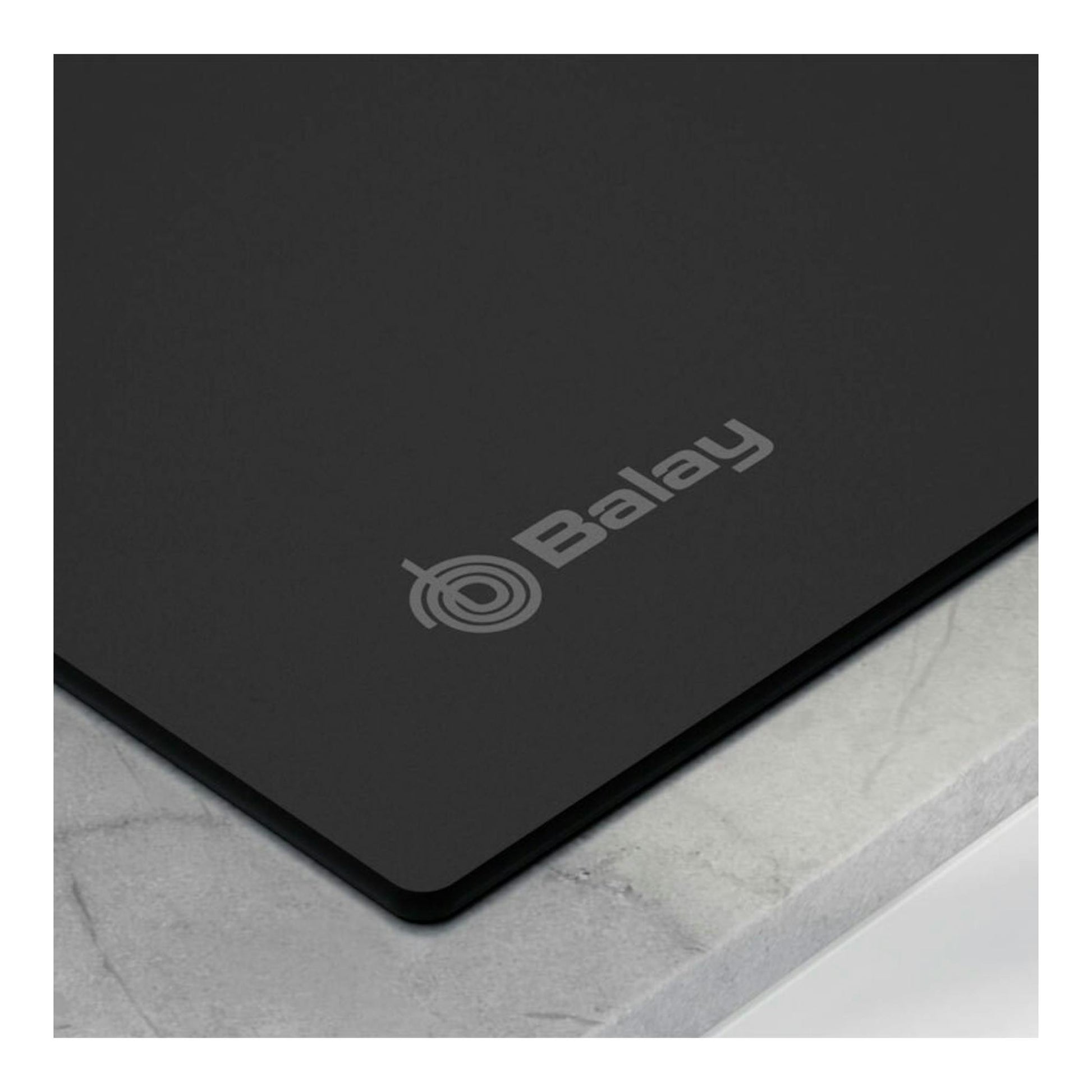 Placa de inducción Balay 3EB967MH negra, vista en ángulo de un borde sobre encimera gris.