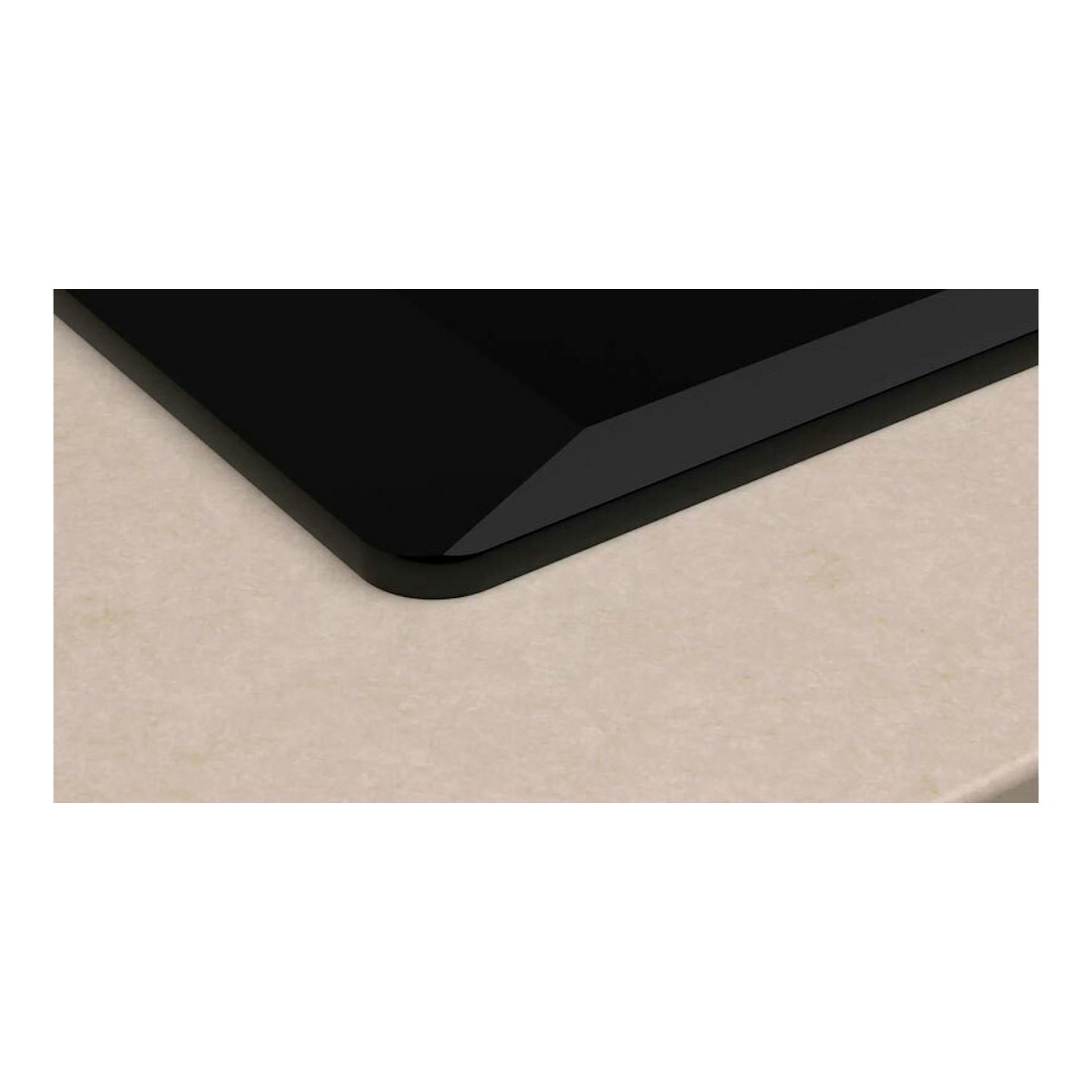 Primer plano de la esquina de una placa de inducción Balay 3EB977LH negra sobre encimera beige.