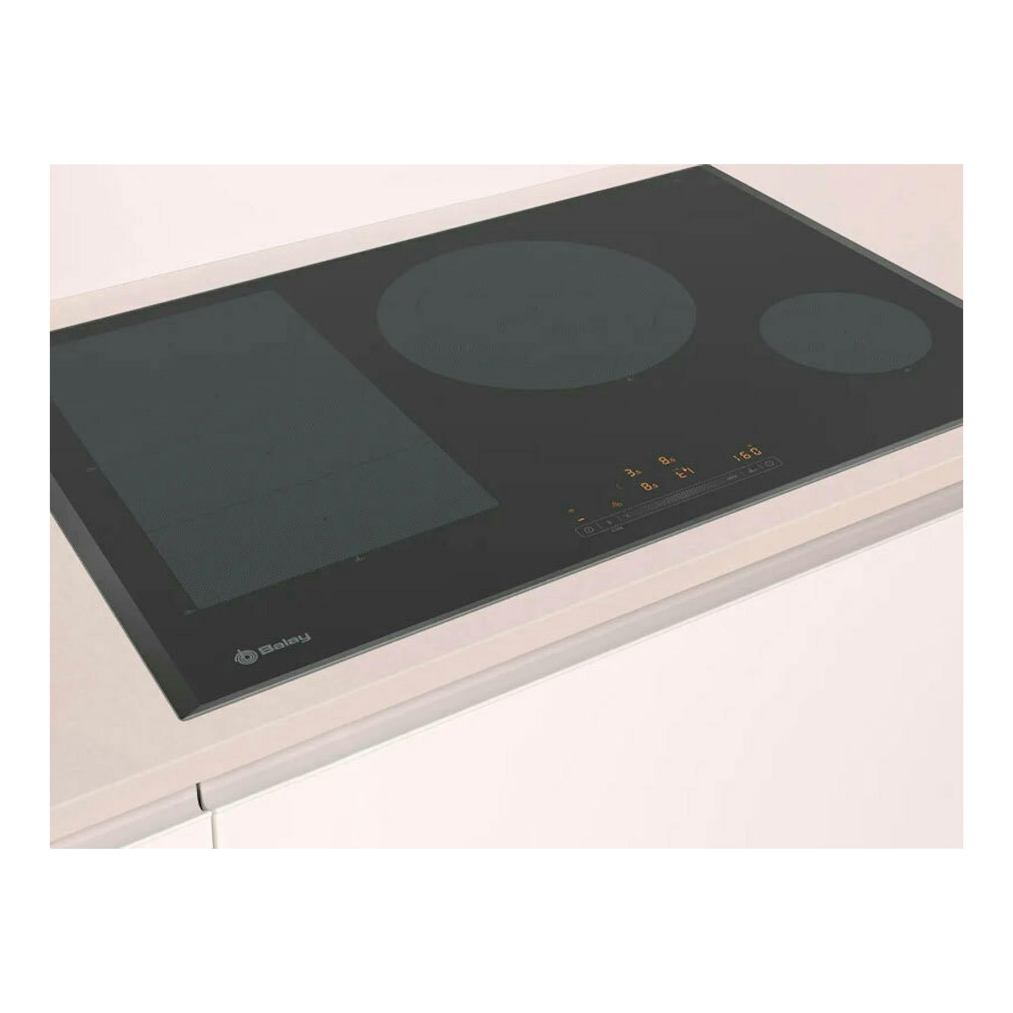 Placa de inducción Balay 3EB989LH negra, vista superior inclinada, con tres zonas de cocción.