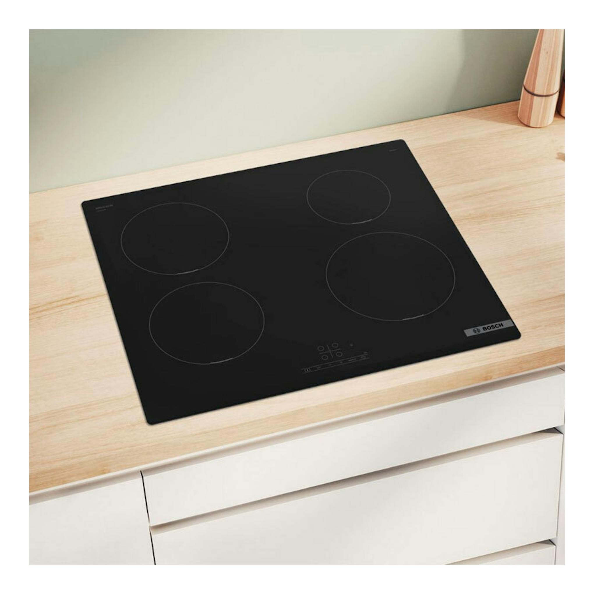 Placa de inducción Bosch PIE611BB5E negra, vista cenital inclinada, con cuatro zonas de cocción.