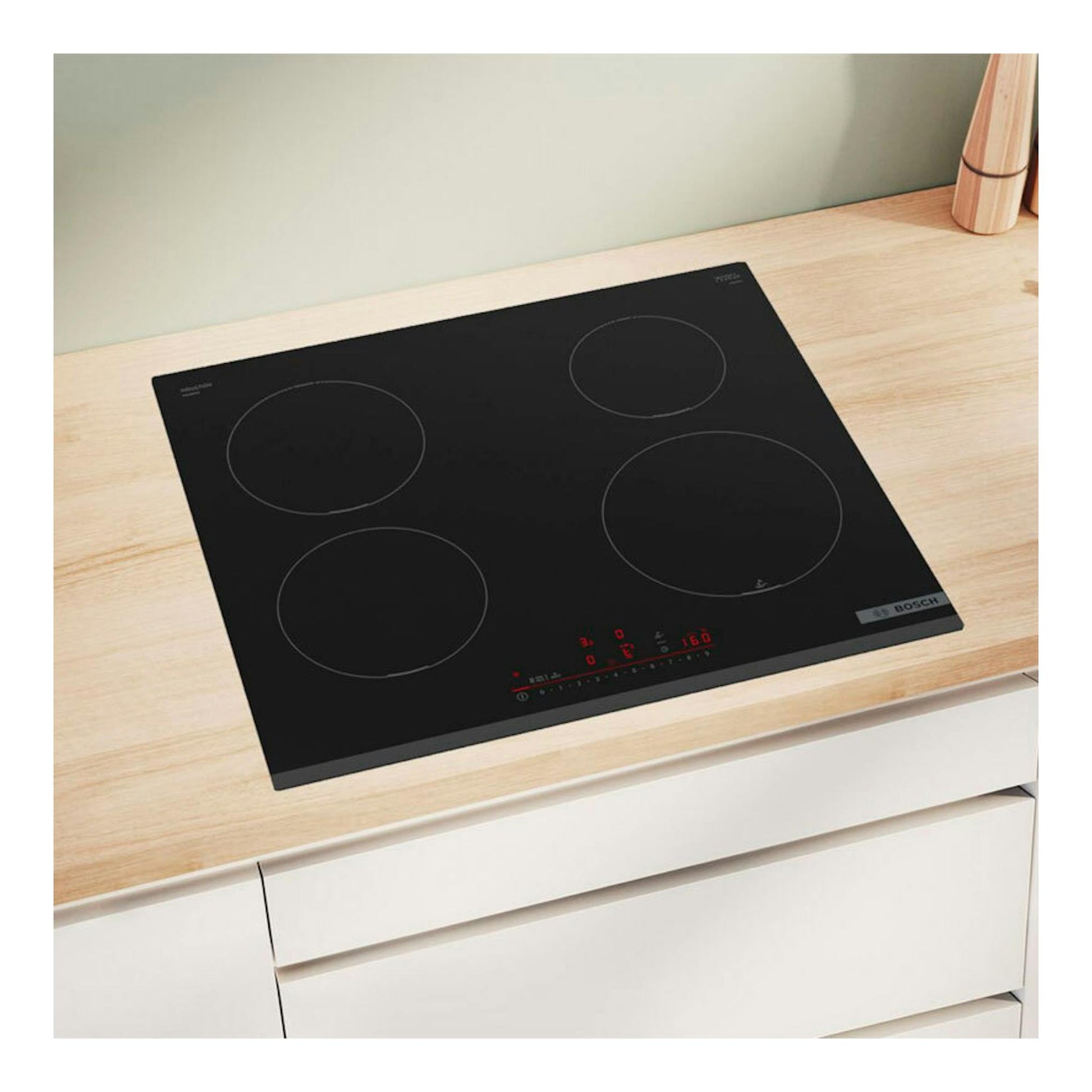 Placa de inducción Bosch PIE631HC1E negra, vista superior en ángulo, con 4 zonas de cocción sobre encimera de madera.
