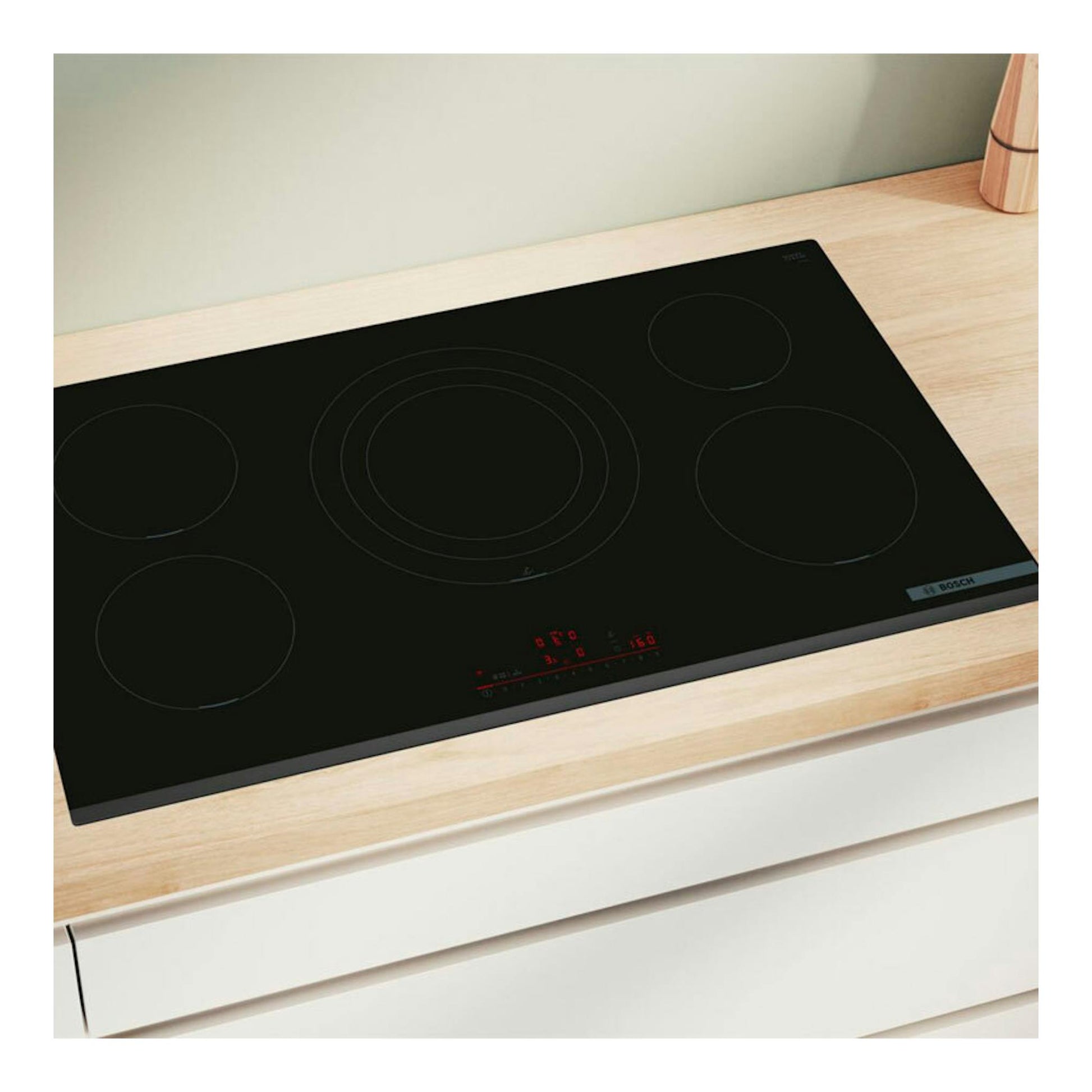 Placa de inducción Bosch PIV931HC1E negra, vista en ángulo sobre encimera de madera, con cinco zonas.