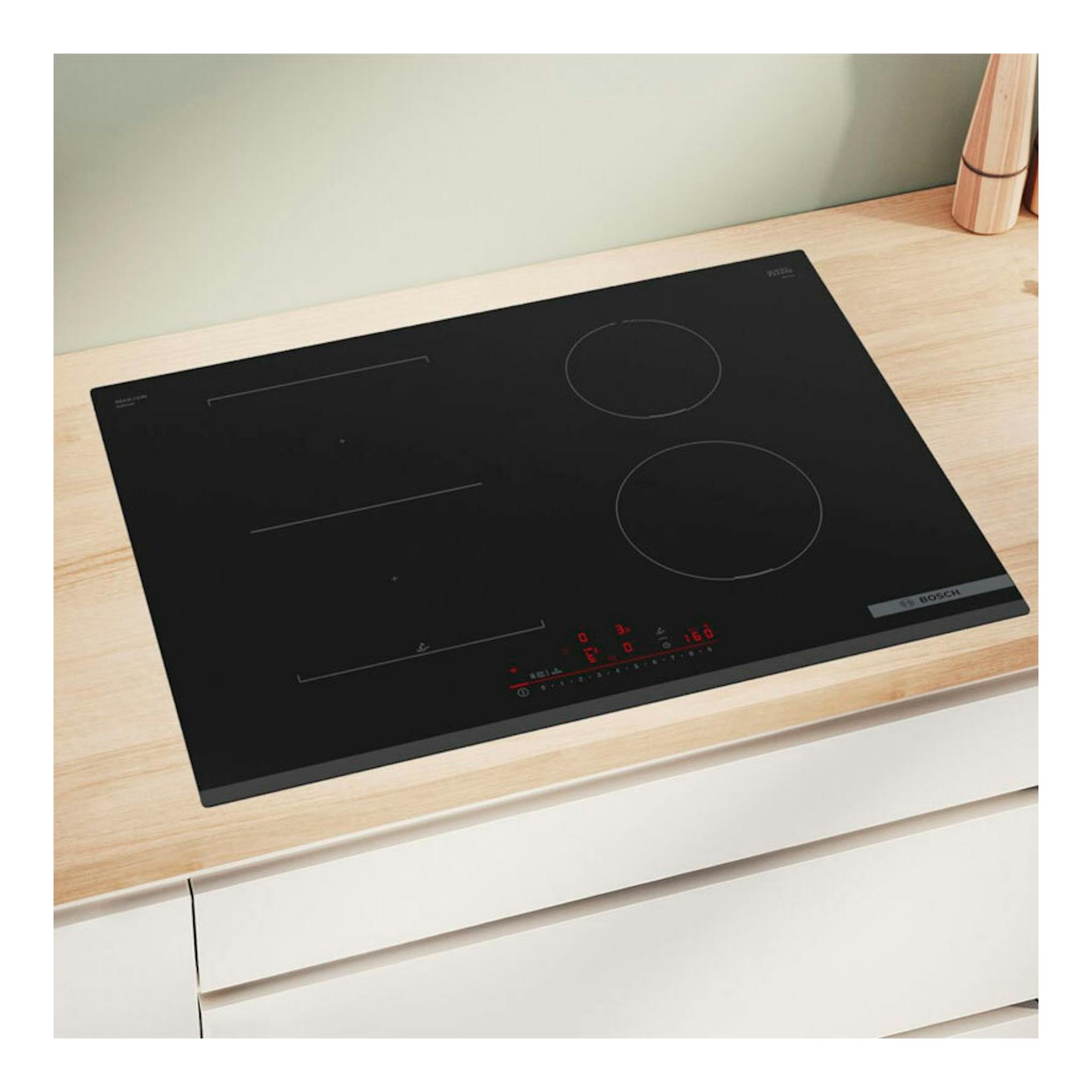 Placa de inducción Bosch PVS731HC1E negra, vista en ángulo sobre encimera de madera clara.