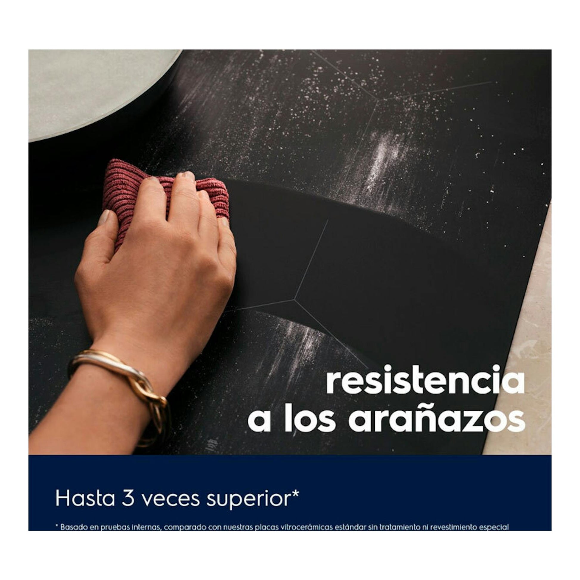 Placa de inducción Electrolux EIT61336CT negra, en ángulo, con una mano limpiando la superficie.