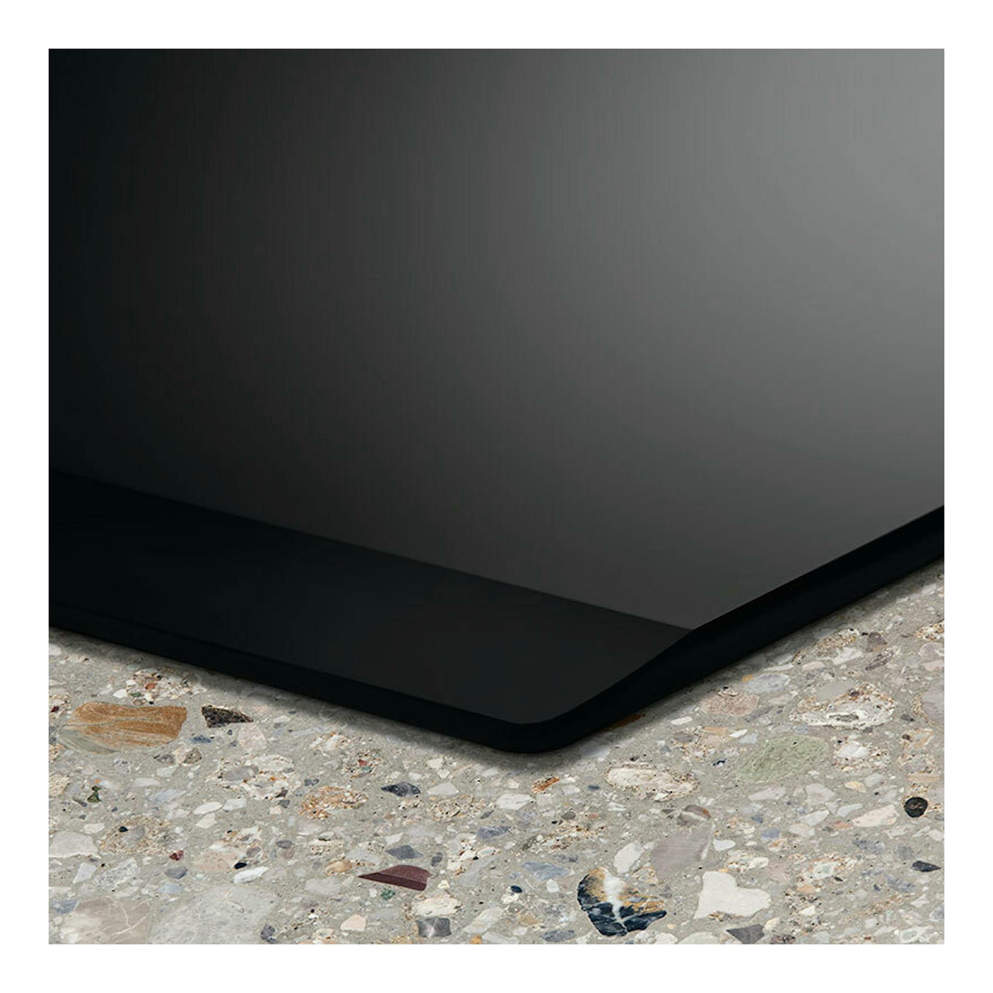 Placa de inducción Electrolux EIV633 negra, vista en esquina sobre encimera de terrazo.