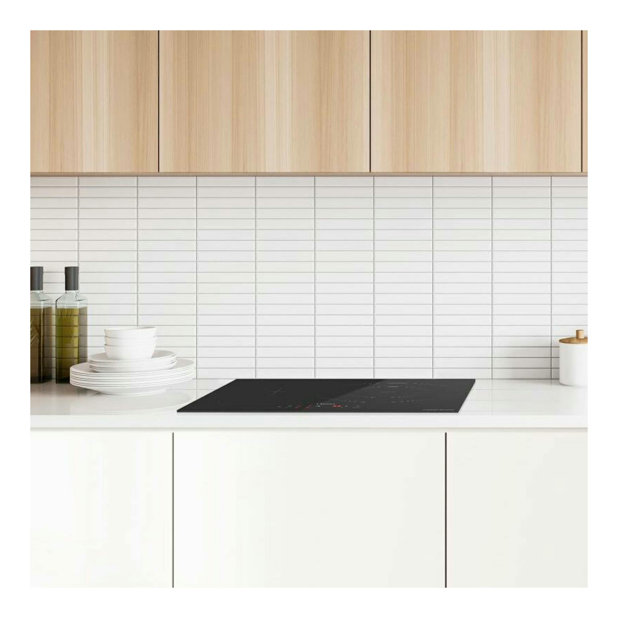 Placa de inducción Midea MIH740T279K0 negra, vista frontal, empotrada en encimera blanca de cocina.