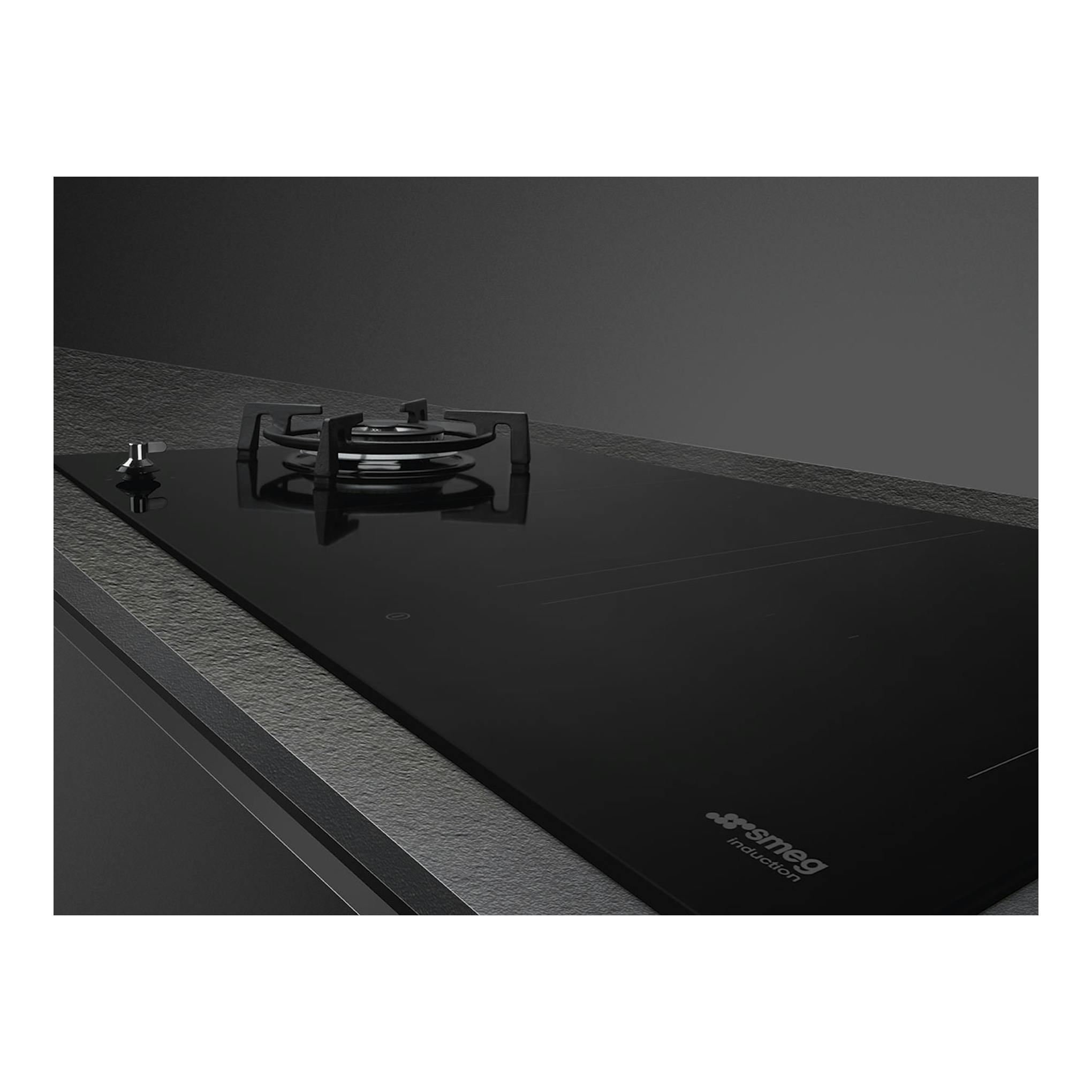 Placa Smeg PM3953D negra, vista en ángulo, con un quemador de gas y zonas de inducción.
