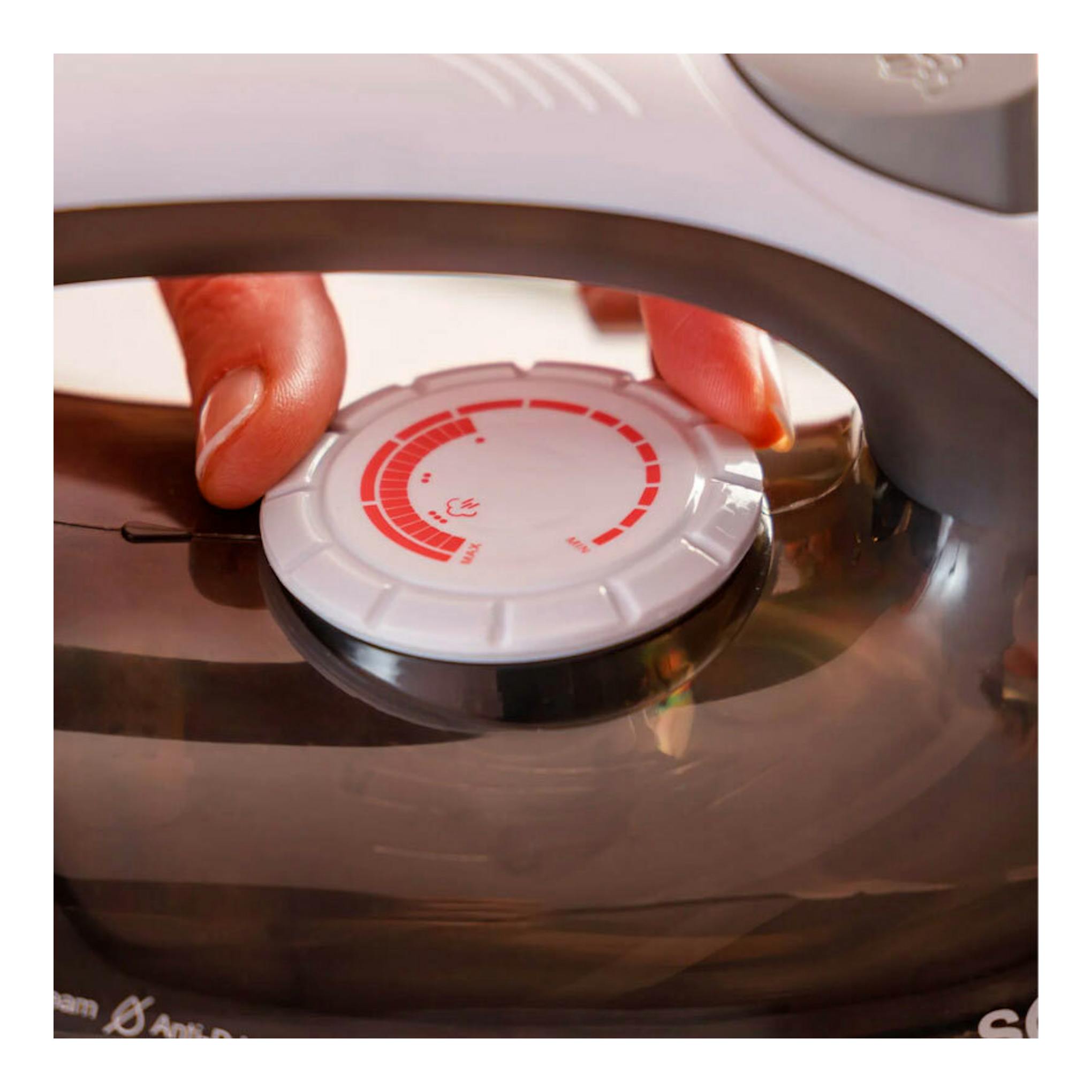 Plancha de vapor Solac PV2400, vista cenital parcial, con dial de temperatura y una mano ajustándolo.