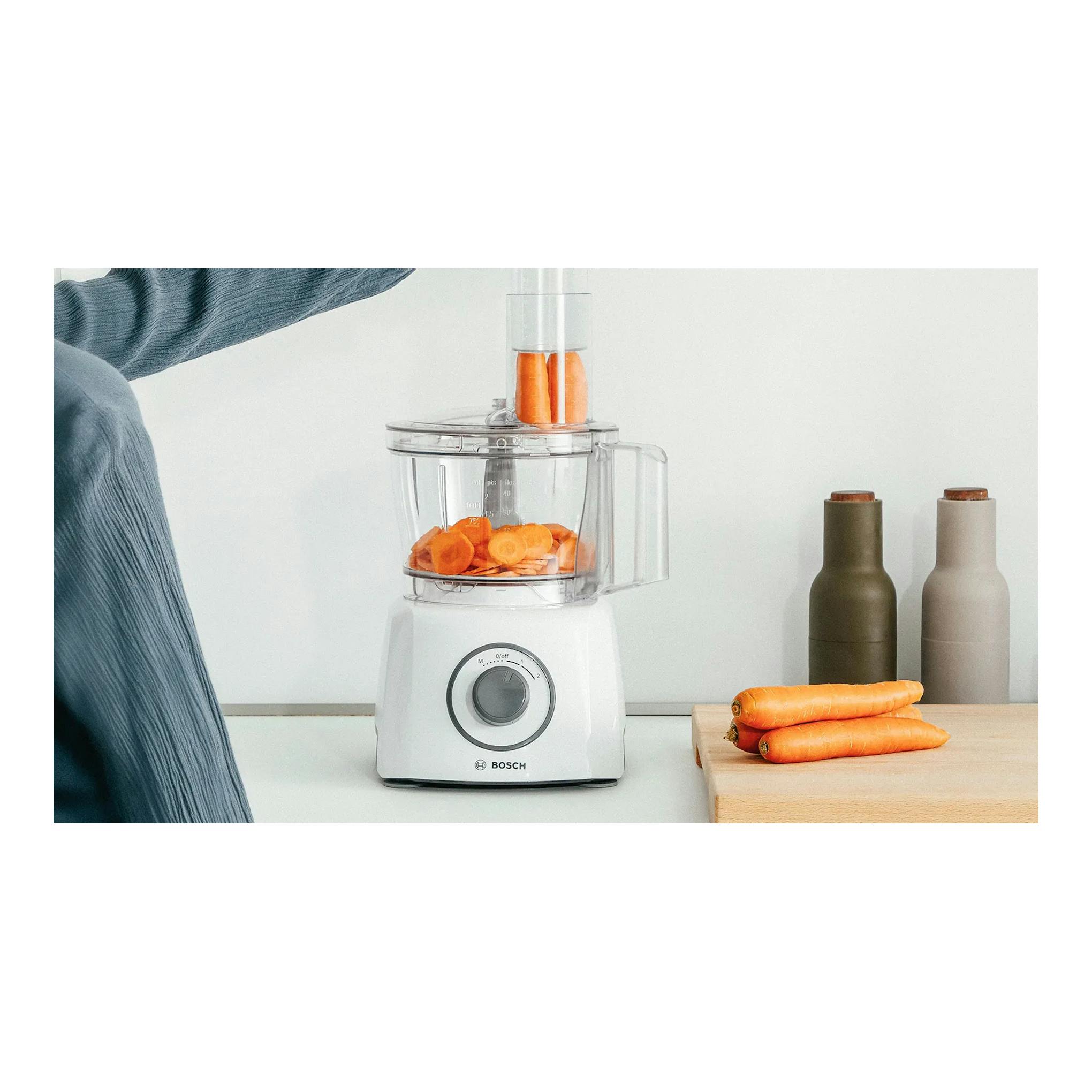 Procesador de alimentos Bosch MultiTalent 3 MCM3100W blanco, vista frontal, con zanahorias en el vaso.