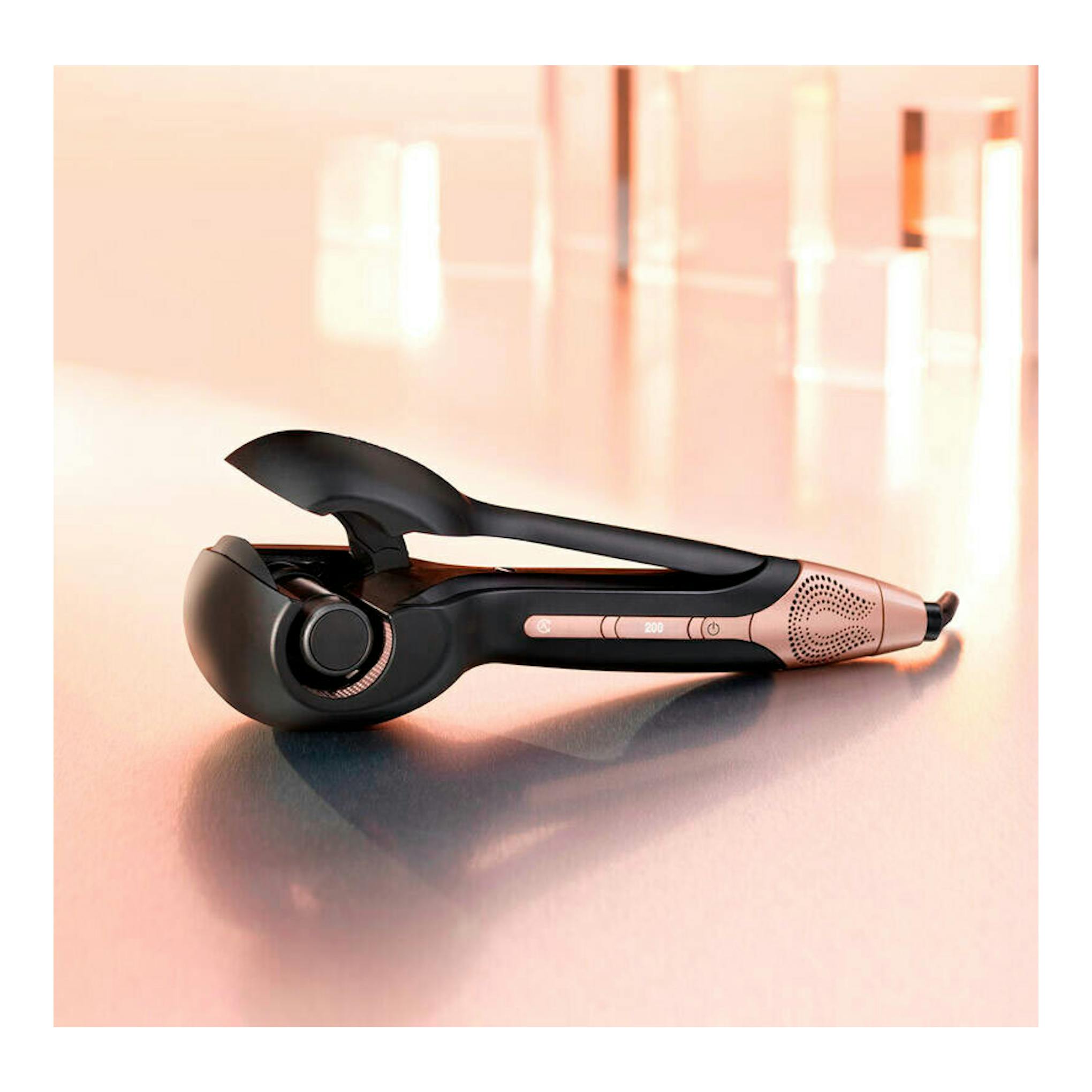 Rizador Babyliss C1900E negro y rosa, visto de perfil sobre una superficie.