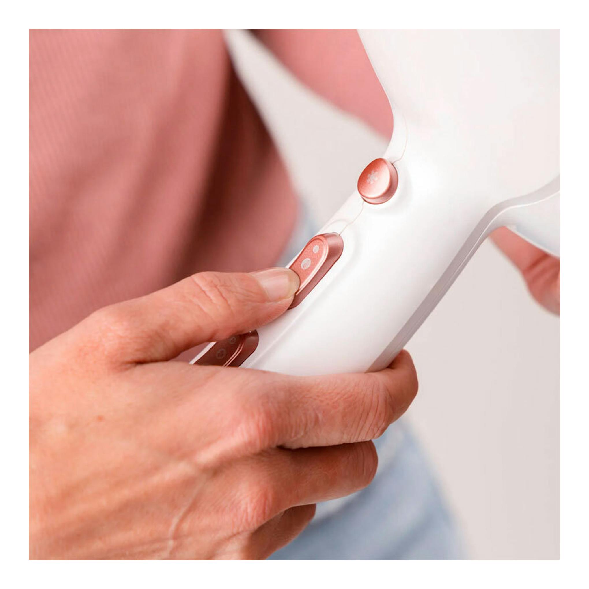 Secador Taurus Fashion 2600 Ionic blanco y rosa, visto en primer plano mientras una mano pulsa los botones.