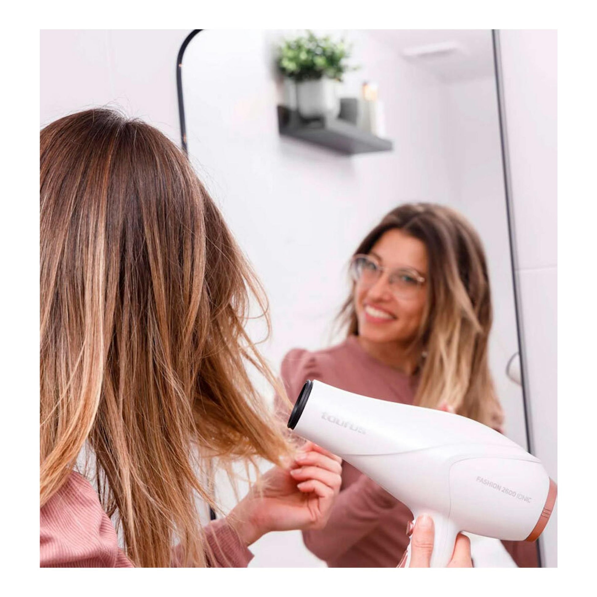 Secador Taurus Fashion 2600 Ionic blanco, de perfil, secando el cabello frente al espejo.