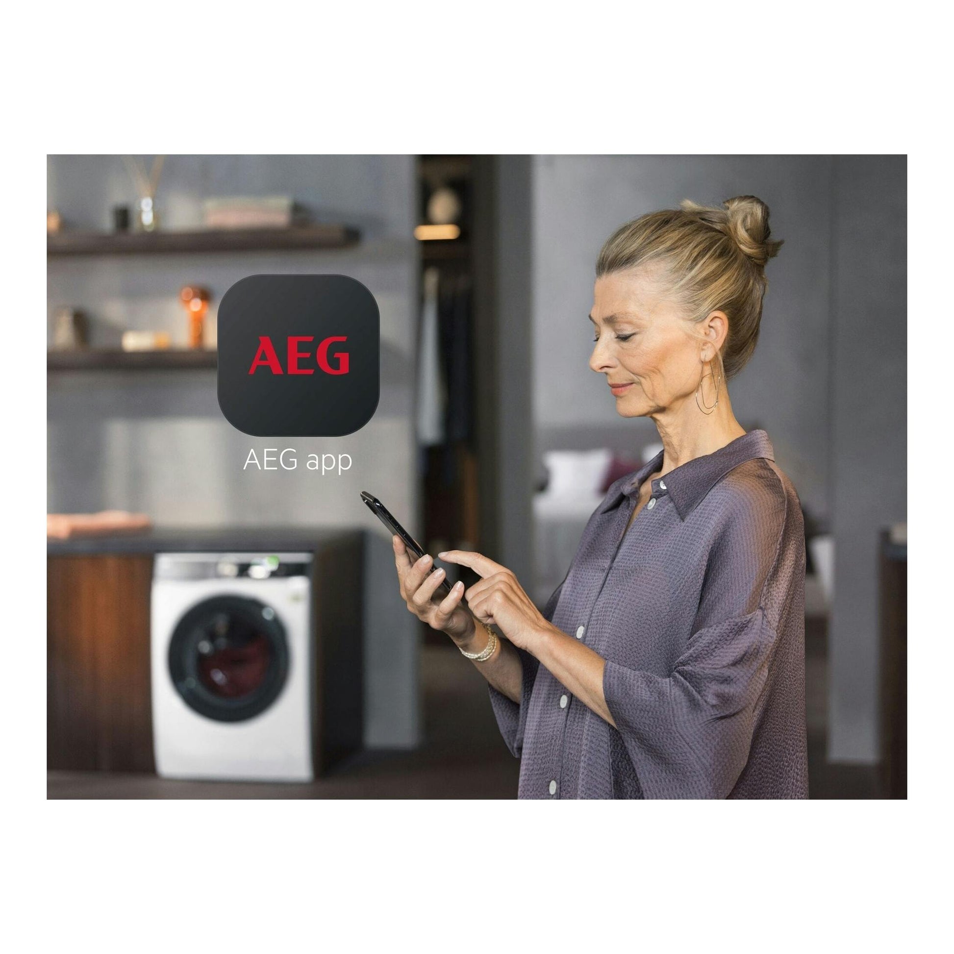 Mujer usando un móvil con la app AEG; al fondo, una secadora AEG blanca con puerta frontal.