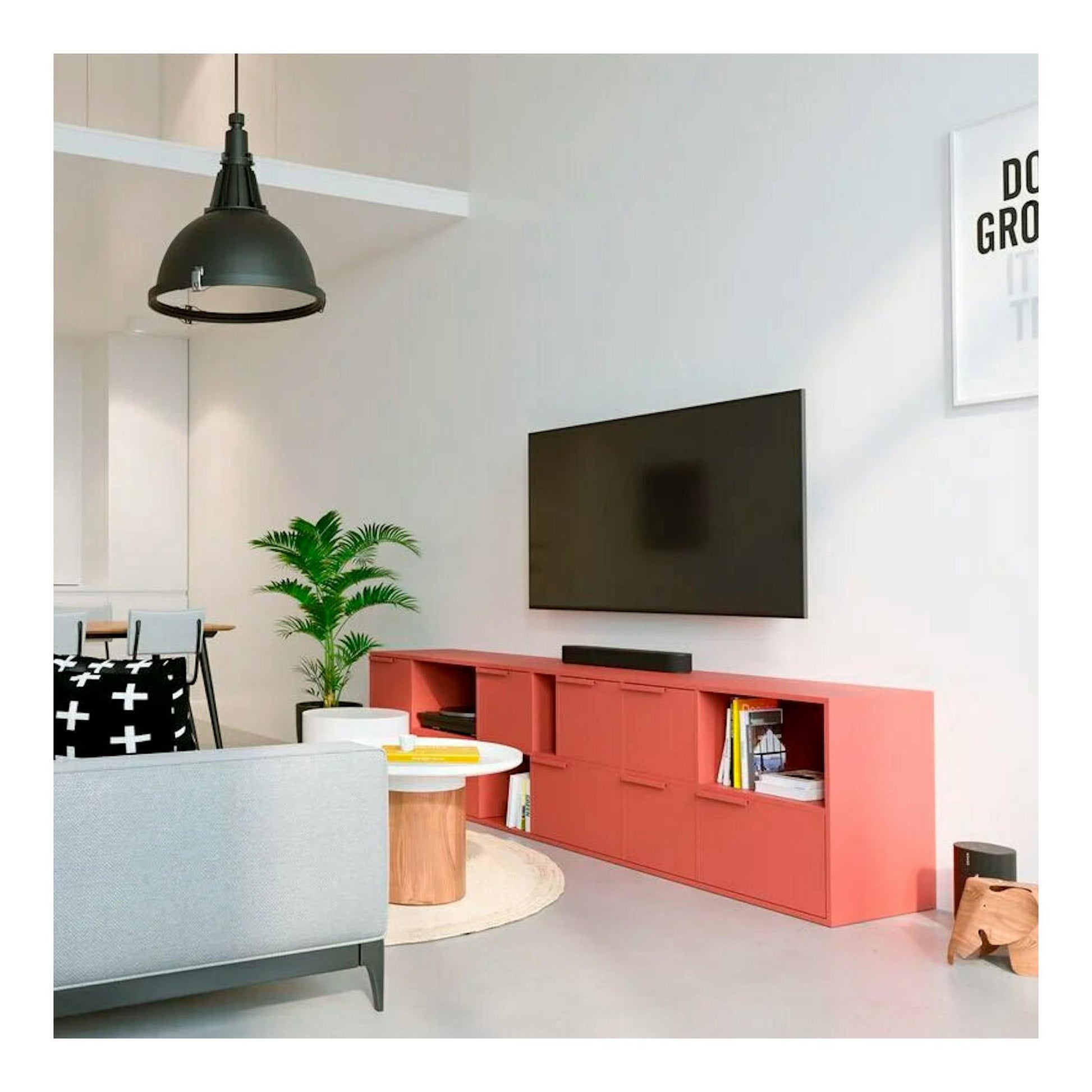 Soporte TV Vogels MA4000 con televisor negro montado en pared, sobre mueble coral, vista frontal.