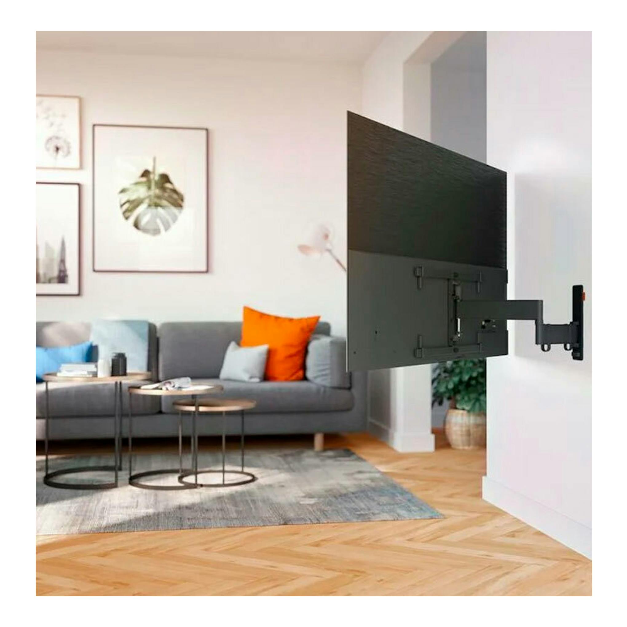 Soporte de pared para TV Vogels TVM 3663 negro, con brazo articulado, visto de lado en una sala.