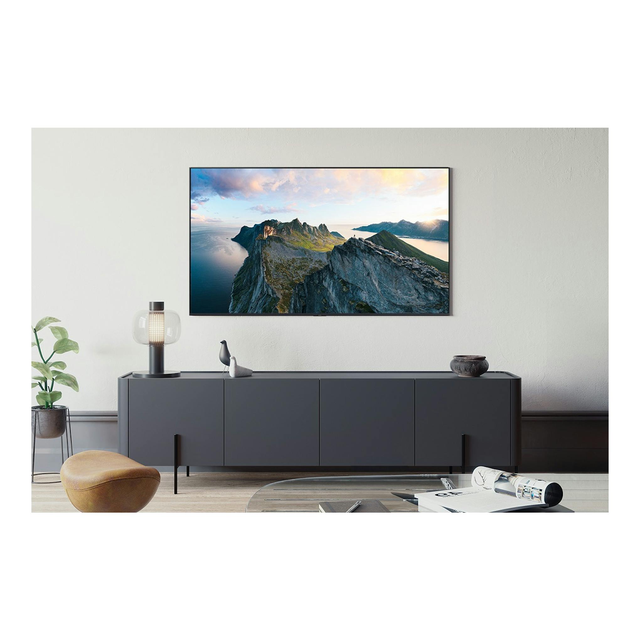 Televisor Samsung TQ55QN80FAUXXC negro, montado en pared, vista frontal con paisaje montañoso.