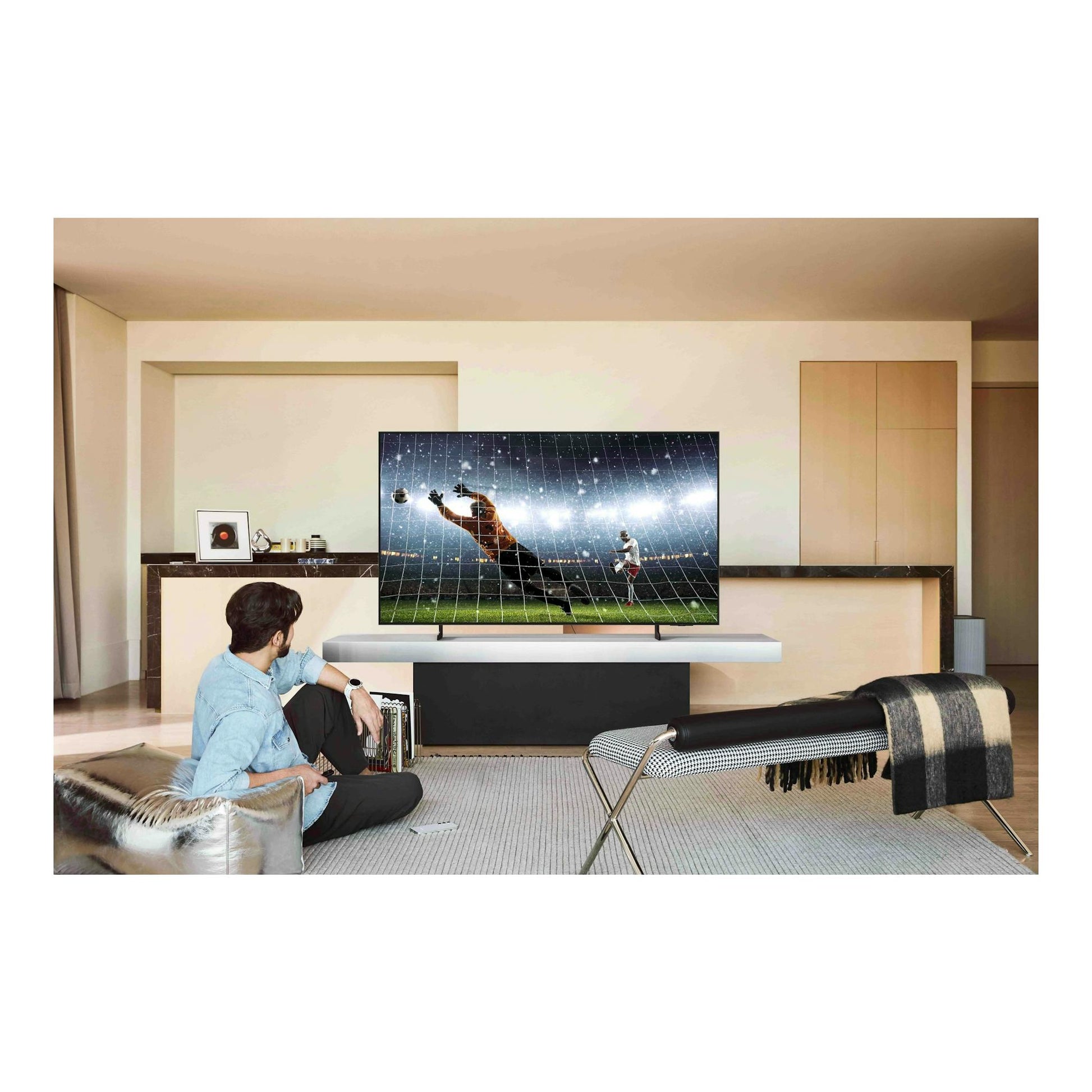 Televisor Samsung TQ55S85FAUXXC OLED en salón moderno, vista frontal, reproduciendo un partido de fútbol.