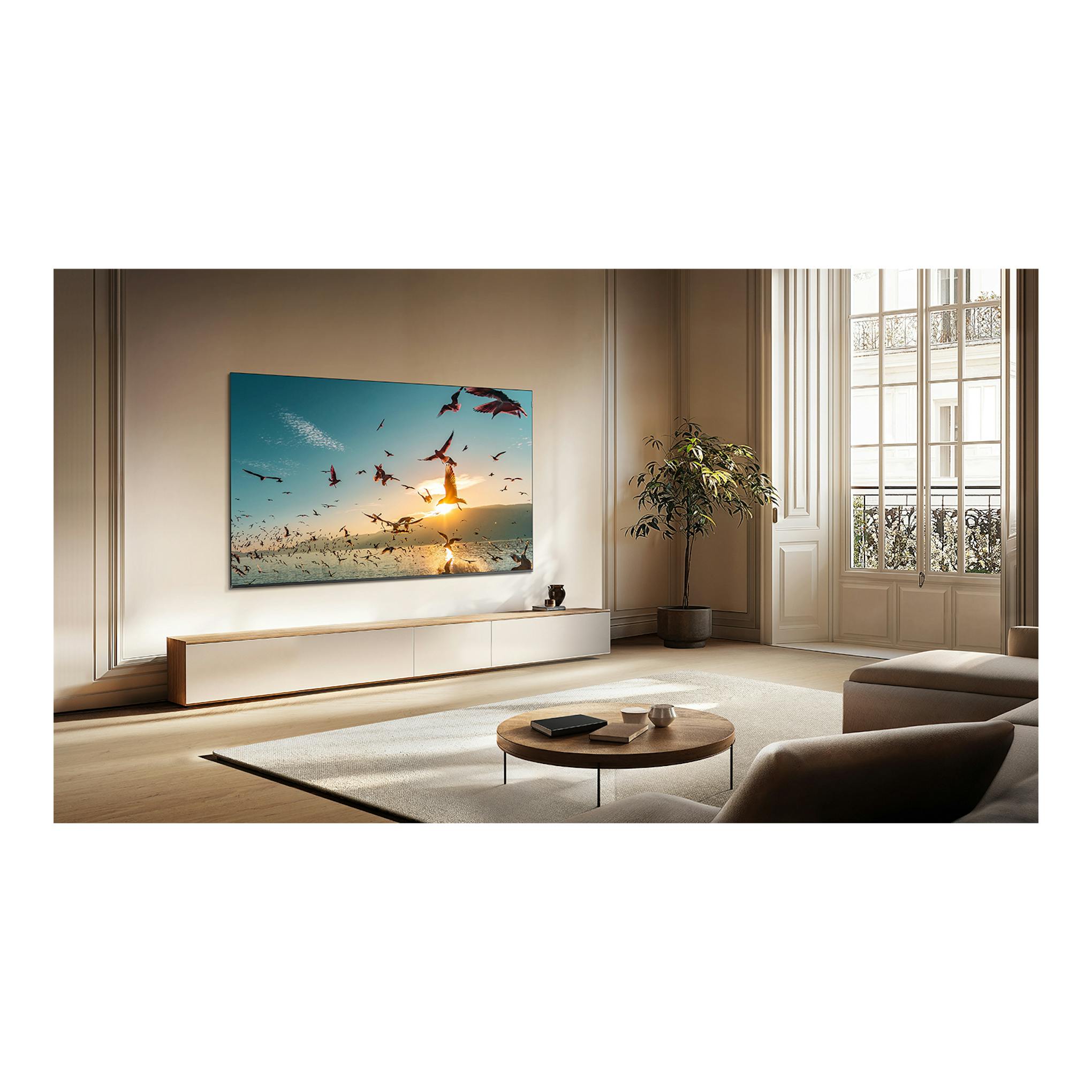 Televisor TCL 55P8K montado en pared, vista frontal en salón, con imagen de aves al atardecer.