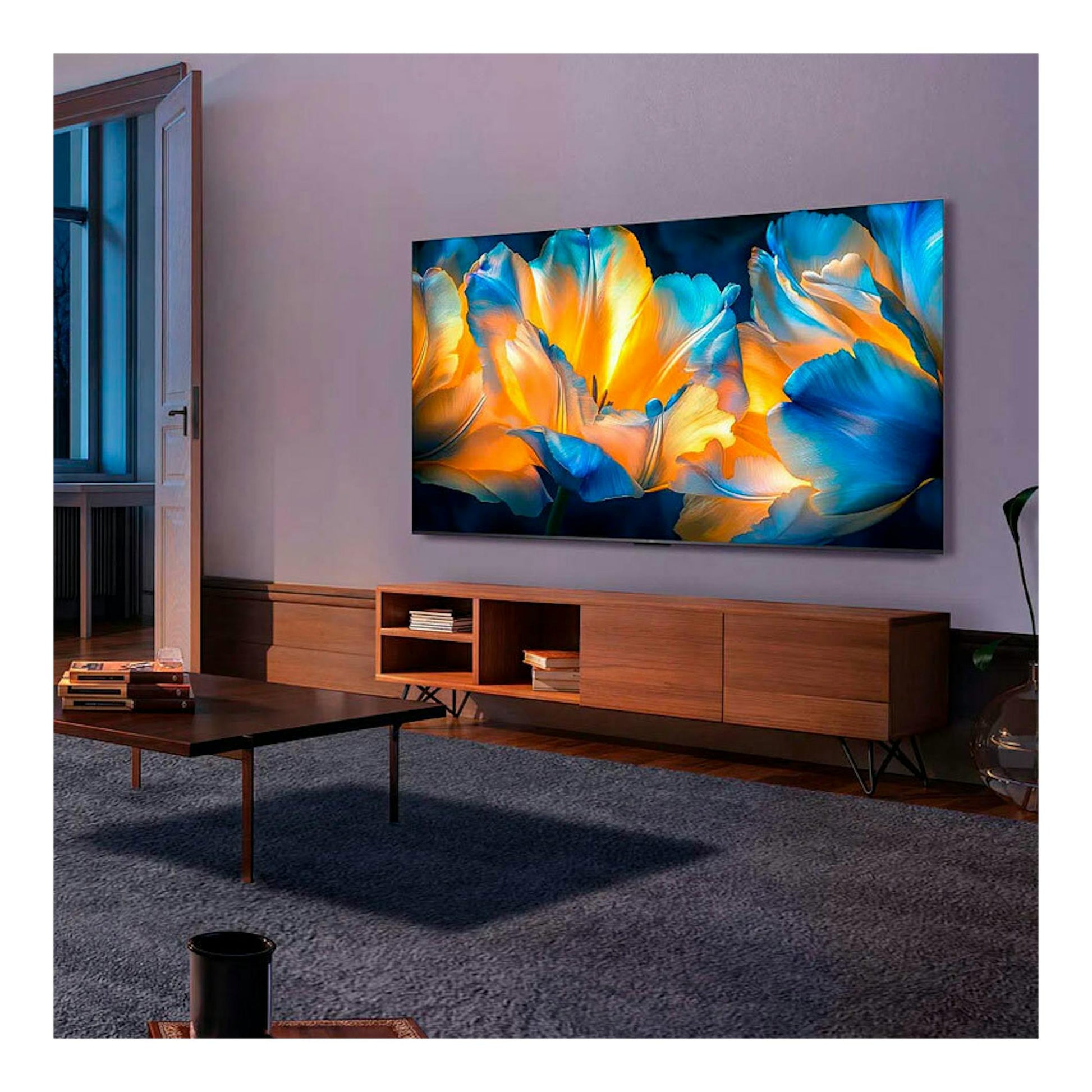 TV TCL 75C6K montado en pared, vista frontal en salón, con pantalla de flores azules y naranjas.