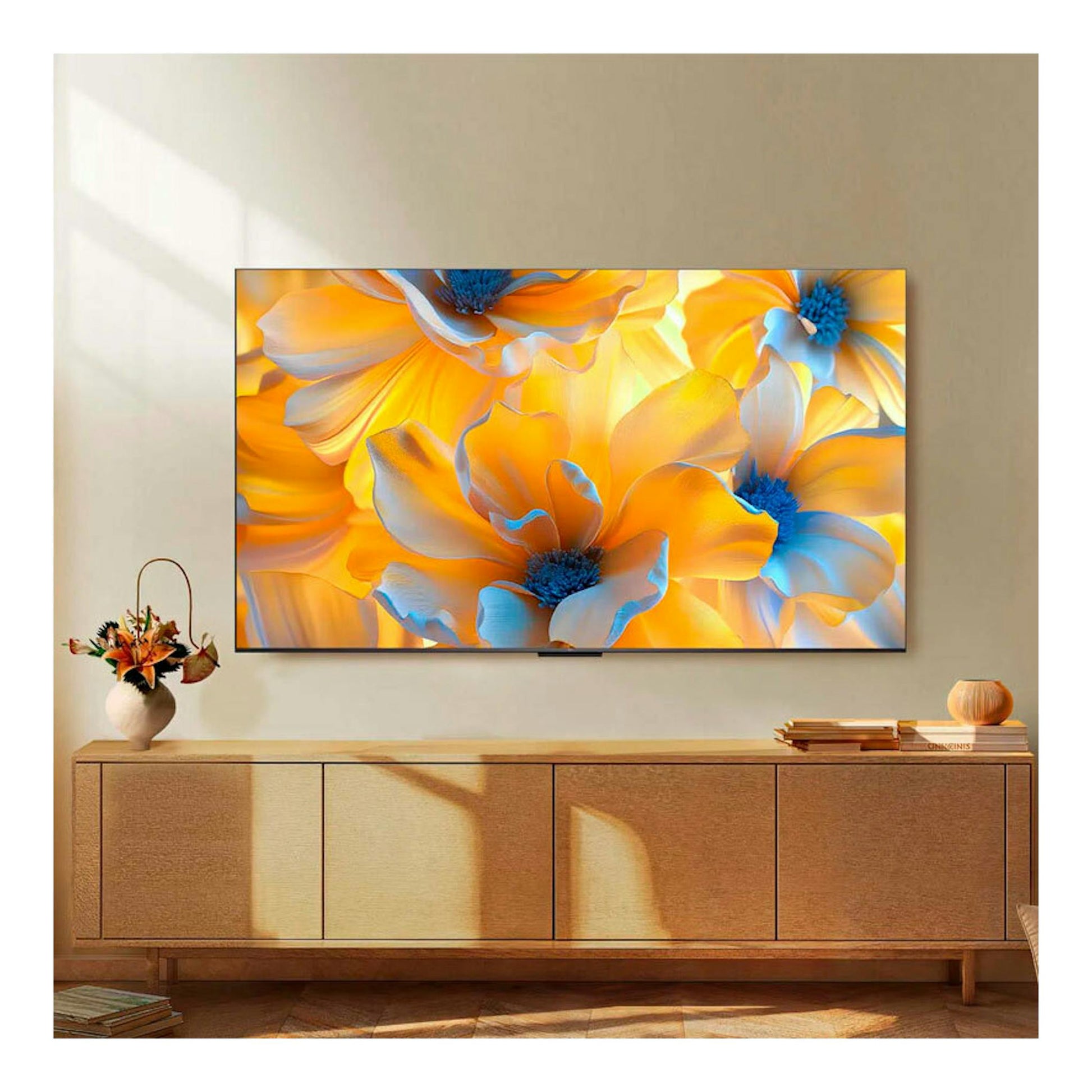 Televisor TCL 85C6K de 85" montado en la pared, vista frontal, con pantalla mostrando flores amarillas y azules.